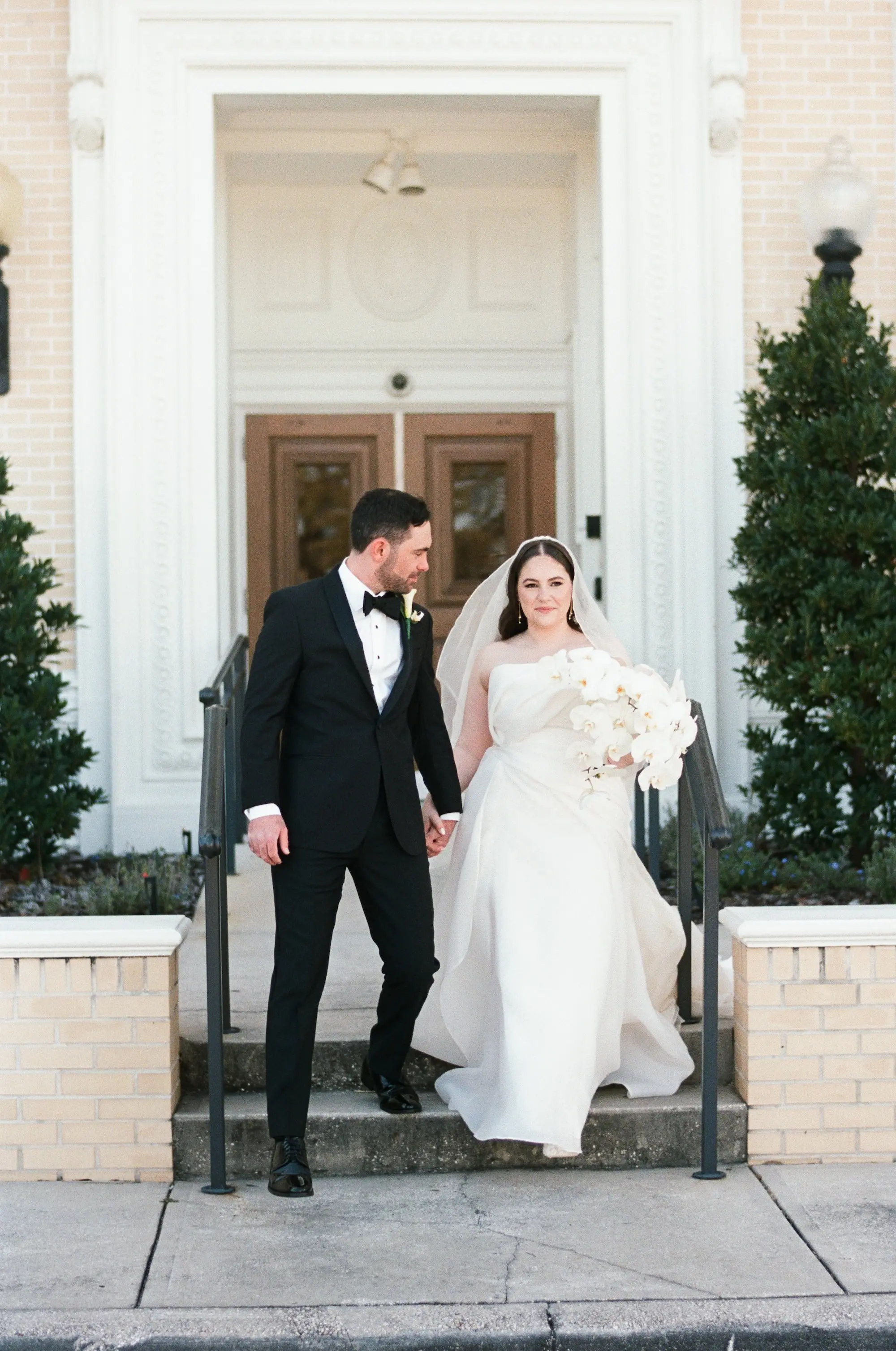Bride and Groom Wedding Portrait | White Orchid Bridal Bouquet Inspiration | Traditional Black and White Groom Tuxedo Ideas | Elegant White Saint Bridal Couture Strapless Wedding Gown Inspiration