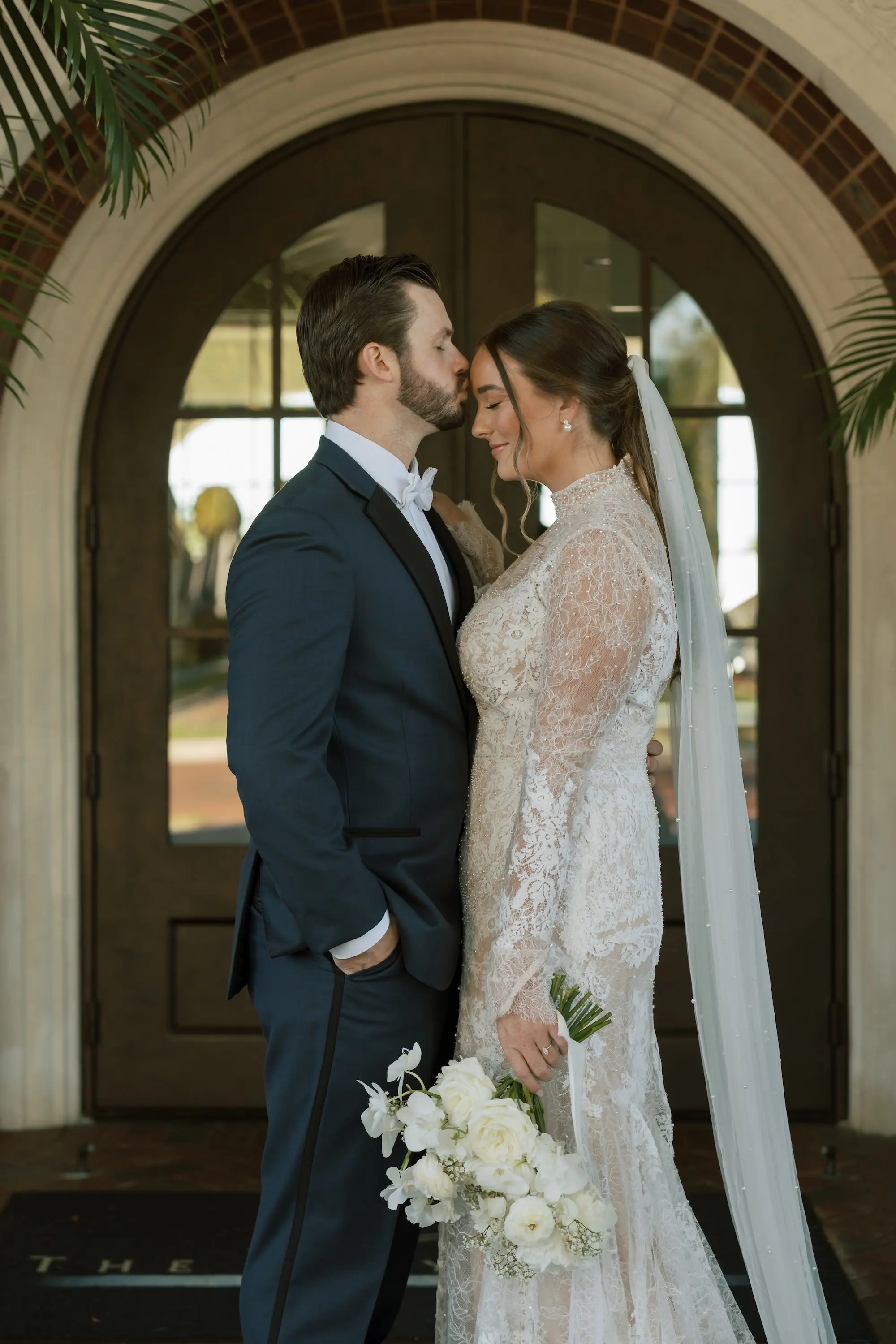 Bride and Groom Wedding Portrait | Fitted Romantic Bohemian White and Nude Lace Watters Wedding Gown with High Neck and Long Sleeves Inspiration | Classic Chiffon Cathedral Length Veil Ideas | Monochromatic White Flower Bouquet Ideas | Tampa Bay Photographer Amber Yonker Photography | Videographer Pine and Forge
