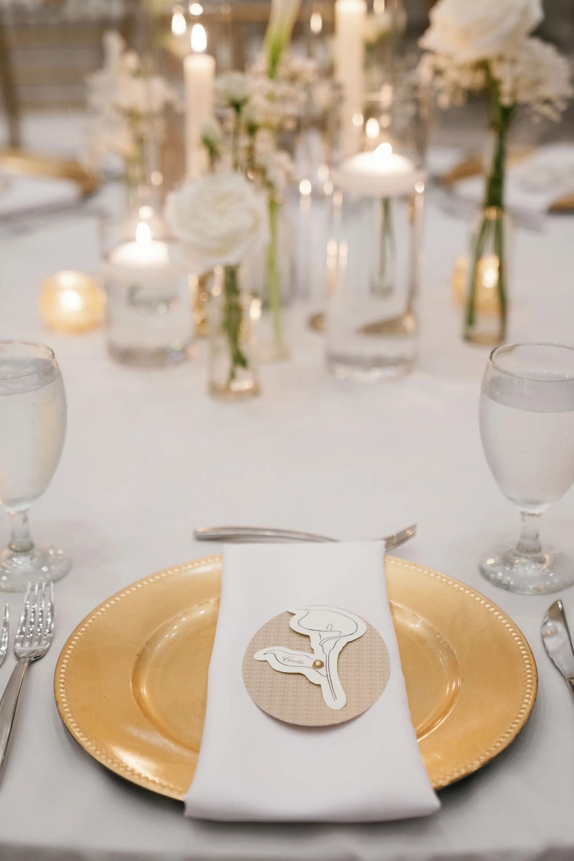 Gold Charger with White Napkin and Silver Flatware Wedding Reception Tablescape Decor Inspiration | Single Stem White Roses with White Baby's Breath Centerpieces with Floating Tea Candles Decor Ideas