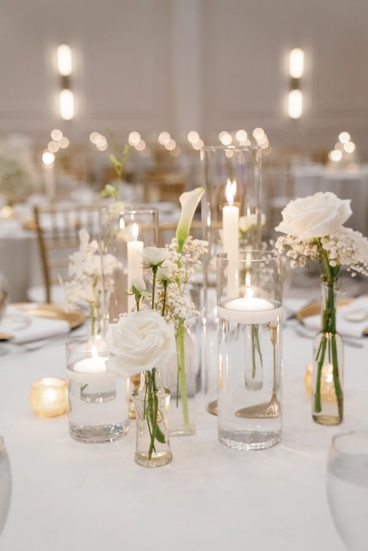 Classic Single Stem White Roses, White Lilies and Baby's Breath in Bud Vases Wedding Reception Centerpiece Decor Inspiration | White Taper Candles and Floating Tea Candles Decor Ideas
