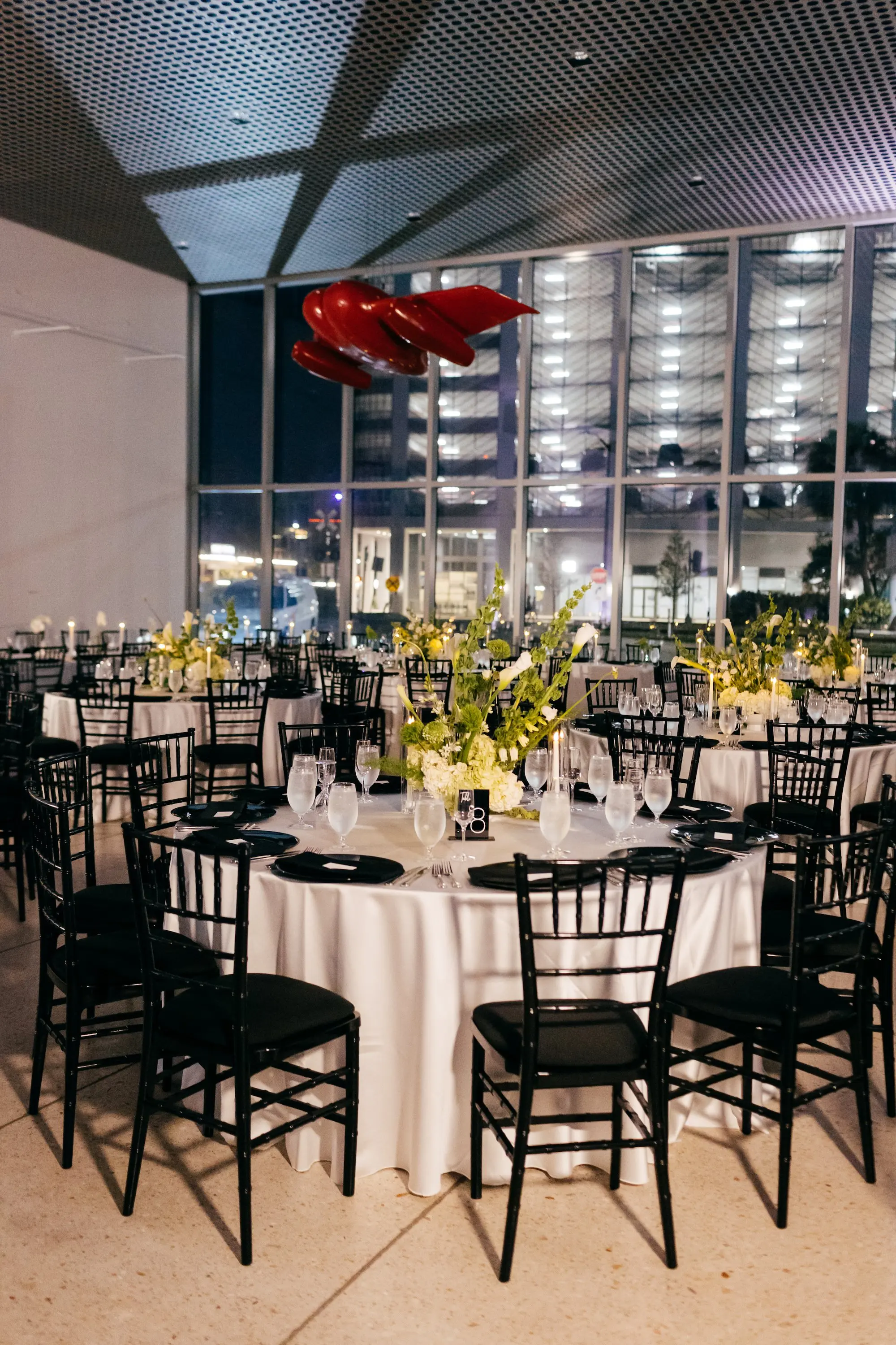 Elegant Modern Black Tie Night Museum Wedding Reception Inspiration | White Linens with Black Napkins and Black Chairs Ideas | Black Acrylic Table Numbers with White Writing Inspiration | White and Green Floral Wedding Reception Centerpieces Ideas | Over The Top Rental Linens | Tampa Bay Event Planner Unique Weddings and Events