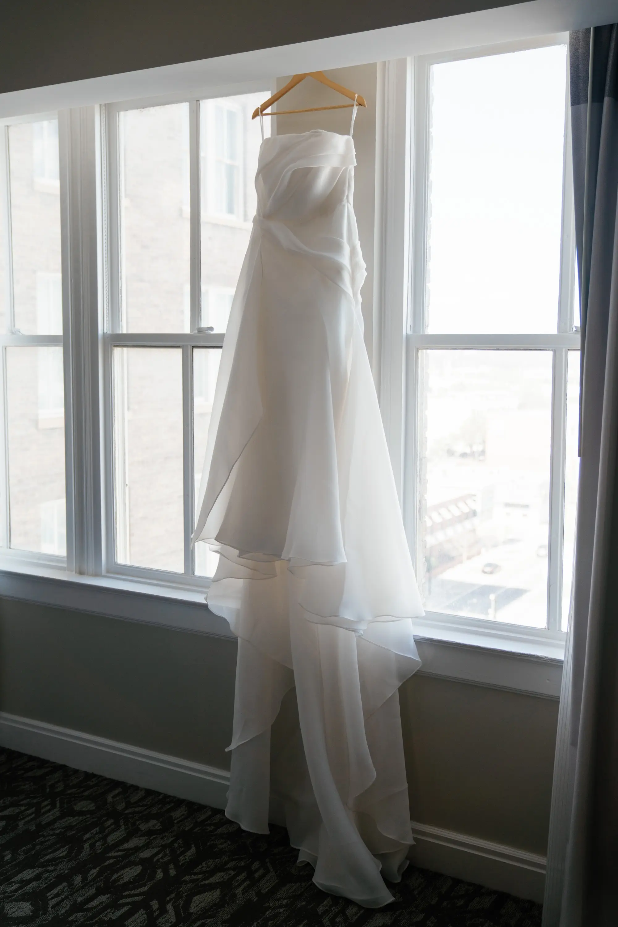 Elegant White Saint Bridal Couture Strapless Wedding Gown Hanging in Front of Window Wedding Portrait