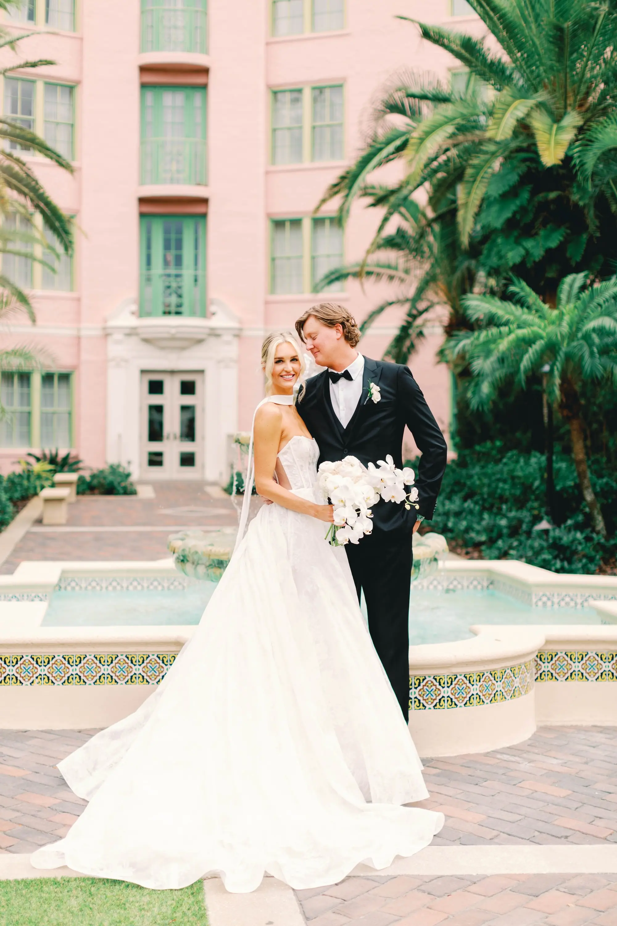 16Classic White and Green Wedding Ideas - Classic, White and Green St. Pete Wedding | The James Museum of Western & Wildlife Art Bride and Groom Wedding Portrait in Front of Downtown Event Venue The Vinoy | Timeless White Roses and Orchids Bridal Bouquet Inspiration | White Strapless Wedding Gown with Scarf and Subtle Side Cutouts Ideas