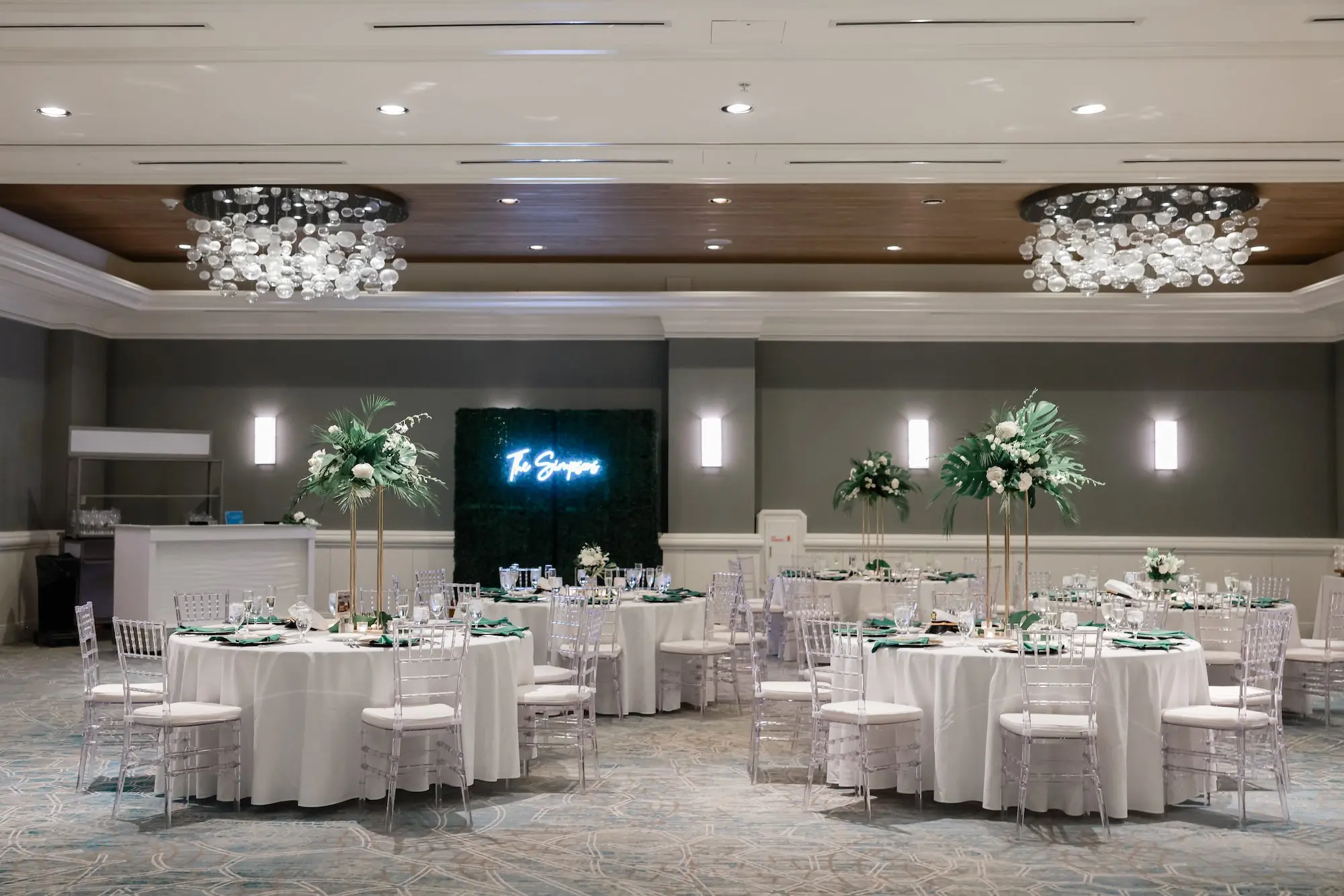 Ivy Wall Backdrop with Last Name Neon Sign Wedding Reception Decor Inspiration | Elegant, Fresh Ballroom Wedding Reception Inspiration | White Linens with Clear Chiavari Chairs Decor Ideas | Tall Gold Vases of White and Green Botanical, Tropical Centerpieces Tablescape Decor Inspiration | Tampa Bay Florist Save The Date Florida | Florida Planner Special Moments Event Planning | Wedding Venue Hyatt Regency Clearwater Beach