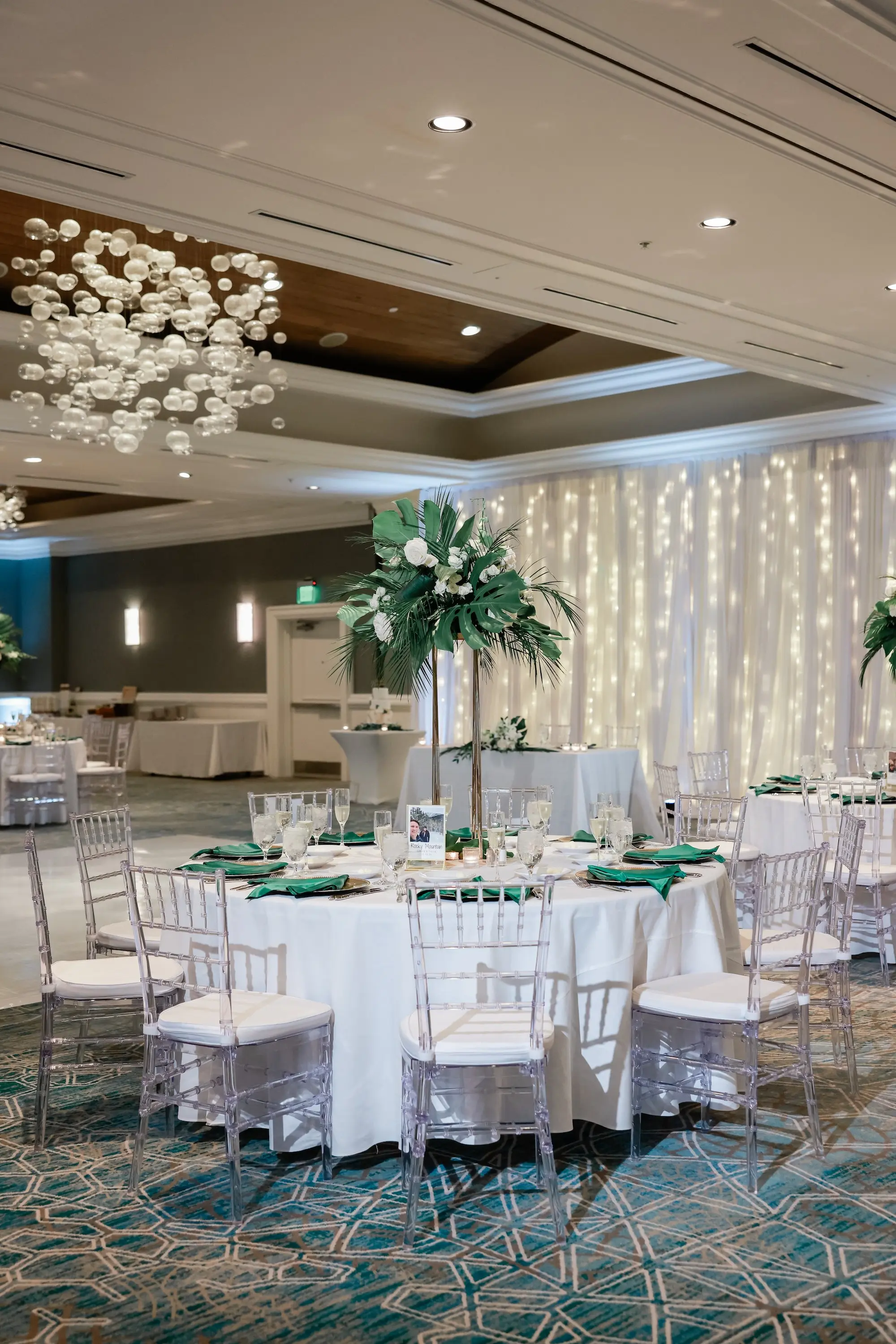 Elegant, Fresh Ballroom Wedding Reception Inspiration | White Linens with Clear Chiavari Chairs Decor Ideas | Tall Gold Vases of White and Green Botanical, Tropical Centerpieces Tablescape Decor Inspiration | Faux Palm Tree Floral Installations Ideas | Tampa Bay Florist Save The Date Florida | Florida Planner Special Moments Event Planning | Wedding Venue Hyatt Regency Clearwater Beach