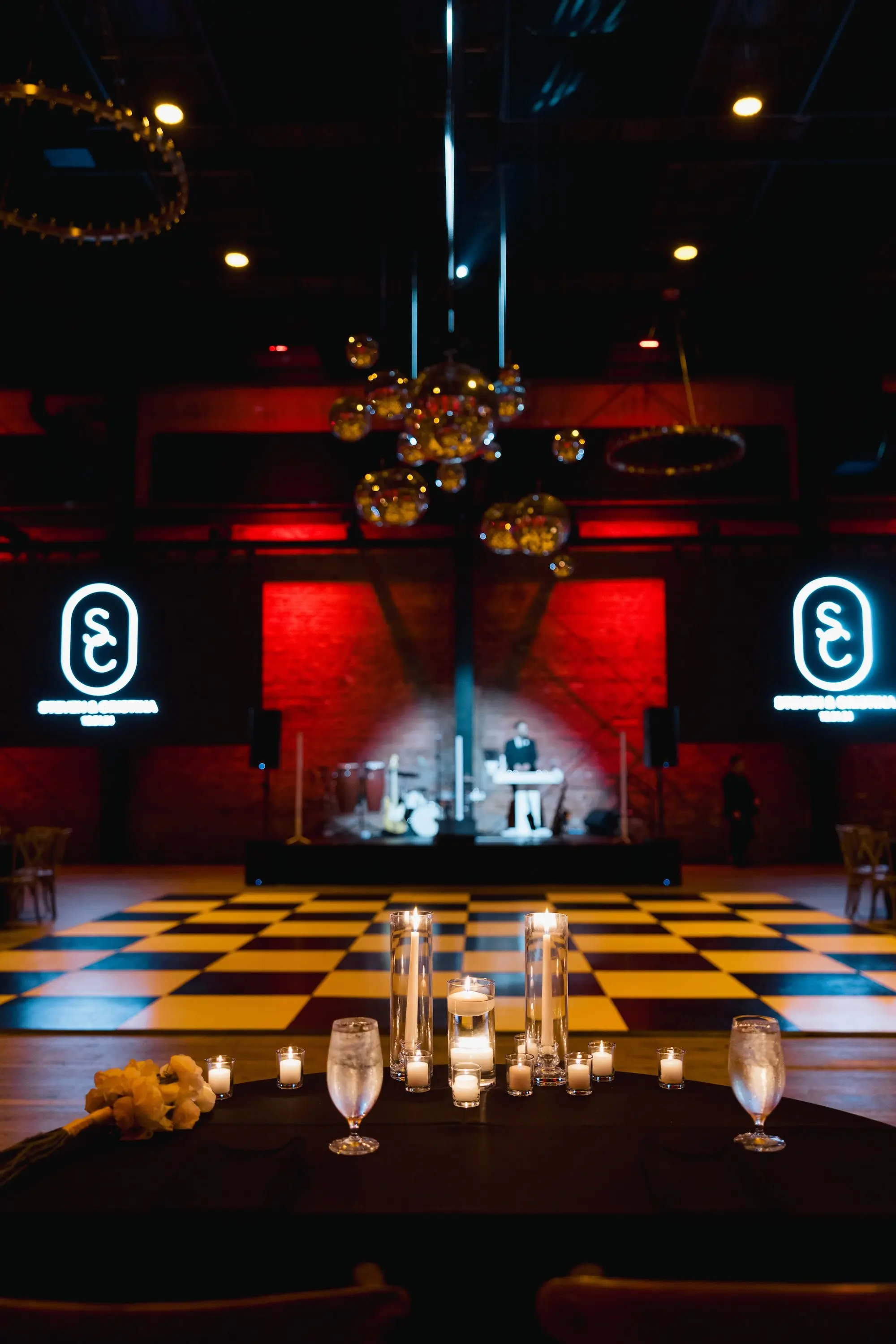 Black and White Checkered Wedding Reception Dance Floor Venue Ideas | Industrial, Exposed Brick Wall Ballroom Wedding Reception | Romantic Floating Tea Candles and Taper Candles in Different Size Glass Vases Table Decor Ideas | New Years Eve Disco Ball Wedding Reception Decor Inspiration | Florida Planner Planner Coastal Coordinating | Downtown Tampa Heights Event Venue Armature Works