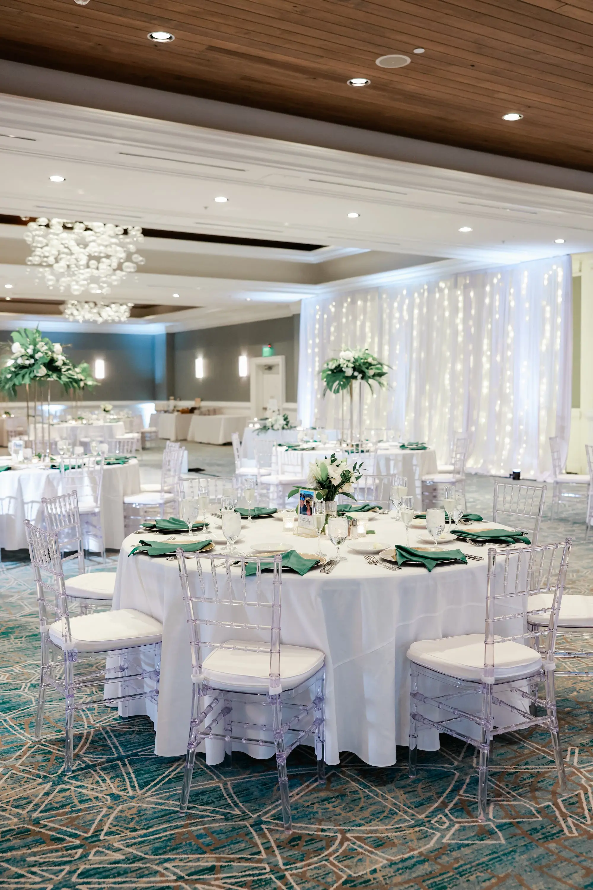 Elegant, Fresh Ballroom Wedding Reception Inspiration | White Linens with Clear Chiavari Chairs Decor Ideas | Tall Gold Vases of White and Green Botanical, Tropical Centerpieces Tablescape Decor Inspiration | Faux Palm Tree Floral Installations Ideas | Tampa Bay Florist Save The Date Florida | Florida Planner Special Moments Event Planning | Wedding Venue Hyatt Regency Clearwater Beach