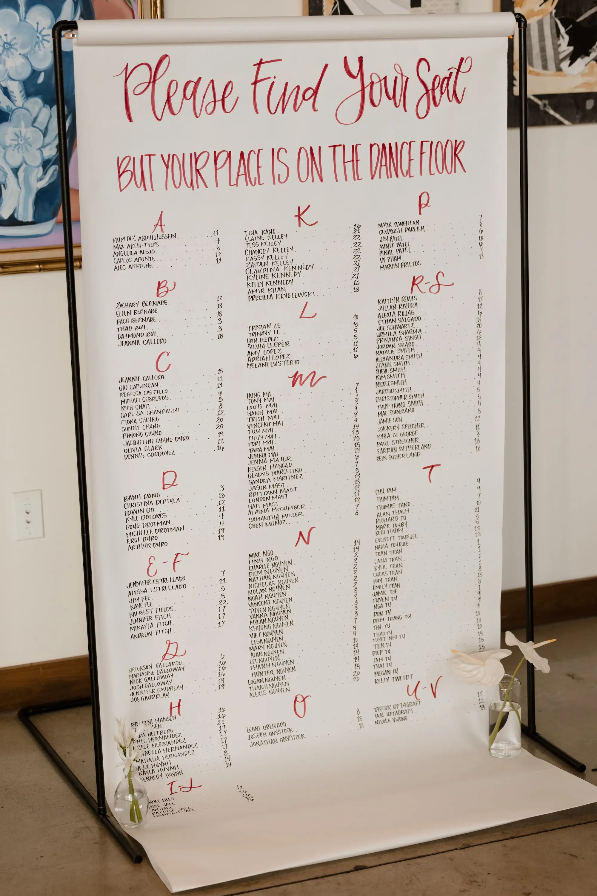 52Modern Romantic Wedding Inspiration - Modern, Moody Fall Ybor City Wedding | Hotel Haya White Butcher Paper Hanging from Black Metal Stand with Black and Red Writing Wedding Reception Seating Chart Inspiration | Single Stem White Flowers Decor Ideas | Tampa Bay Event Planner Wilder Minds Events