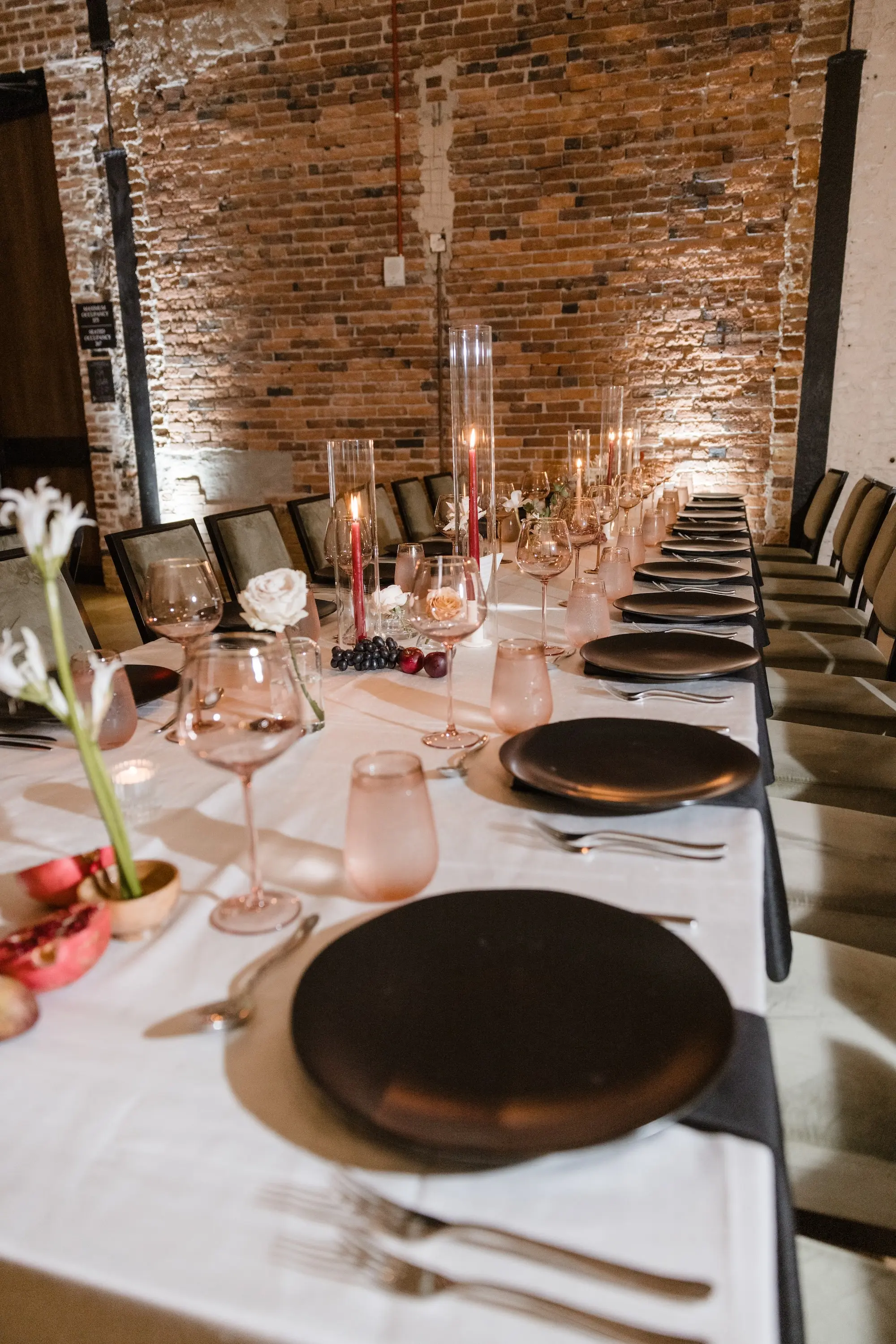 53Modern Romantic Wedding Inspiration Tampa Venue Hotel Haya - Modern, Moody Fall Ybor City Wedding | Hotel Haya Modern, Industrial Exposed Brick Ballroom Wedding Reception | Black Linear Chairs with White Linens and Black Chargers and Napkins Wedding Reception Tablescape Decor Ideas | Red Taper Candles in Glass Vases Decor Inspiration | Venue Hotel Haya | Tampa Bay Event Planner Wilder Minds Events