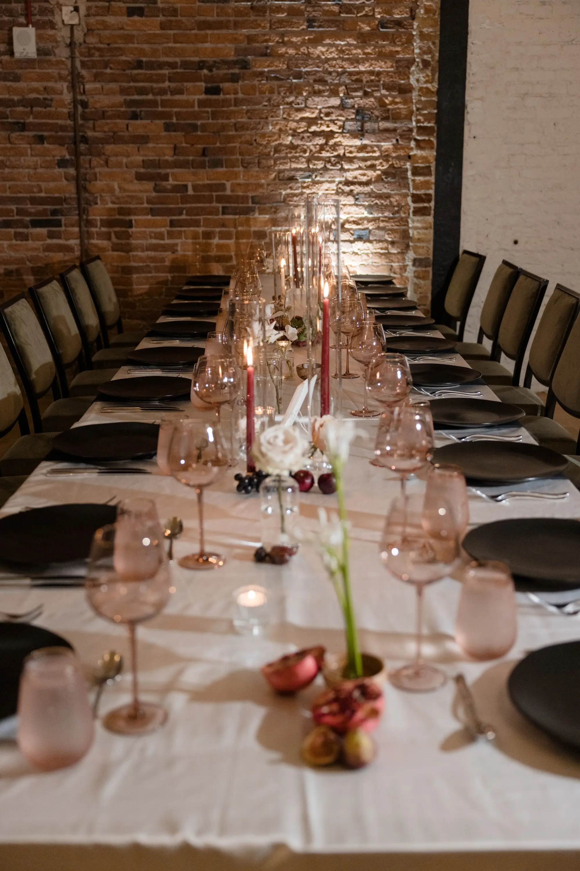 64Modern Romantic Wedding Inspiration - Modern, Moody Fall Ybor City Wedding | Hotel Haya Modern, Industrial Exposed Brick Ballroom Wedding Reception | Black Linear Chairs with White Linens and Black Chargers and Napkins Wedding Reception Tablescape Decor Ideas | Red Taper Candles in Glass Vases Decor Inspiration | Venue Hotel Haya | Tampa Bay Event Planner Wilder Minds Events