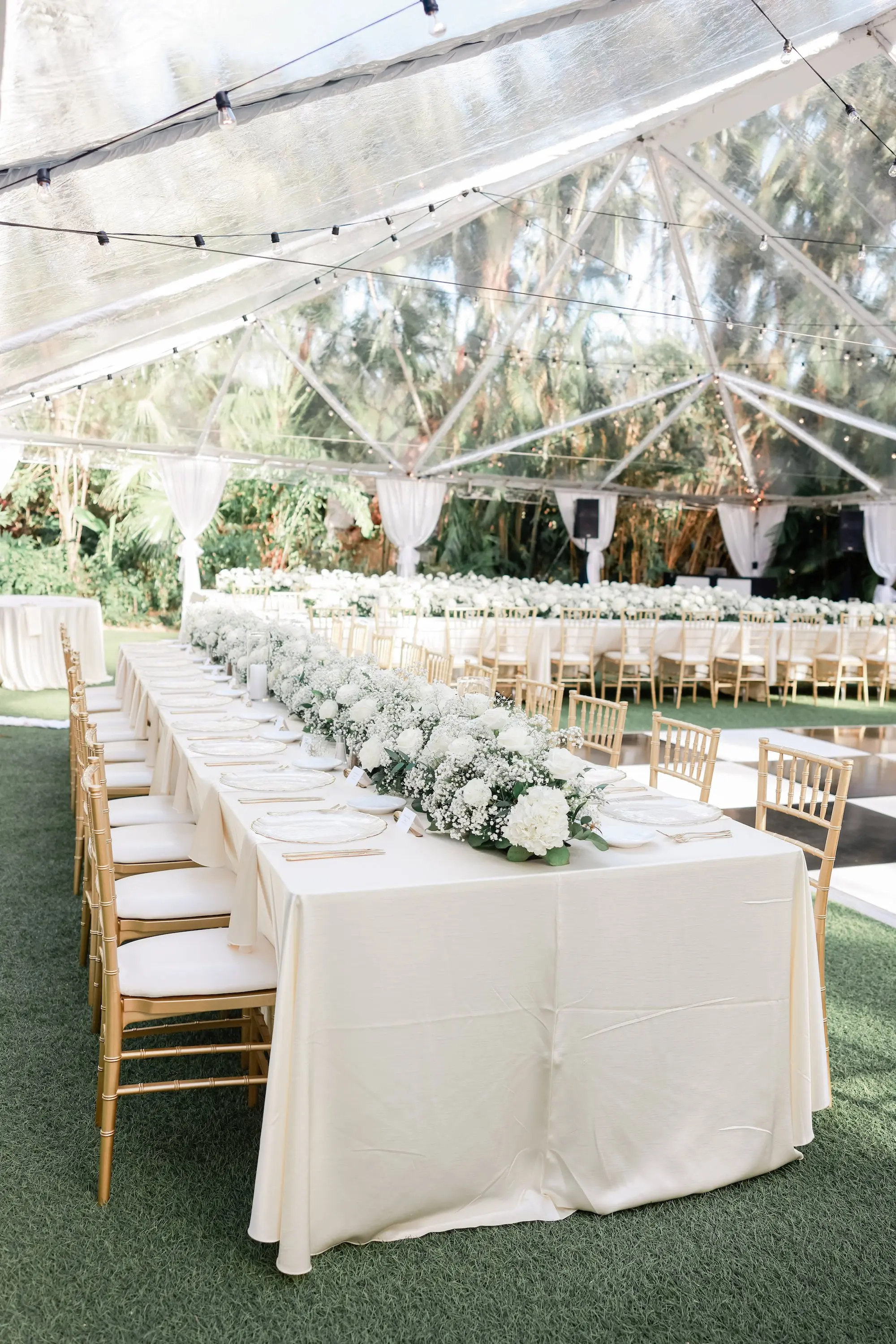 24Elegant Timeless Ivory and Green St Pete Wedding Venue Sunken Gardens - “Best Of” 2025: Wedding Receptions Part 2 Outdoor Tented Wedding Reception with String Lights Decor Inspiration | Gold Chiavari Chairs at Long White Linen Reception Tables Ideas | White Roses with Baby's Breath Centerpiece Garland Reception Decor Inspiration | Tampa Bay Rentals Fiesta Solutions Event Rentals