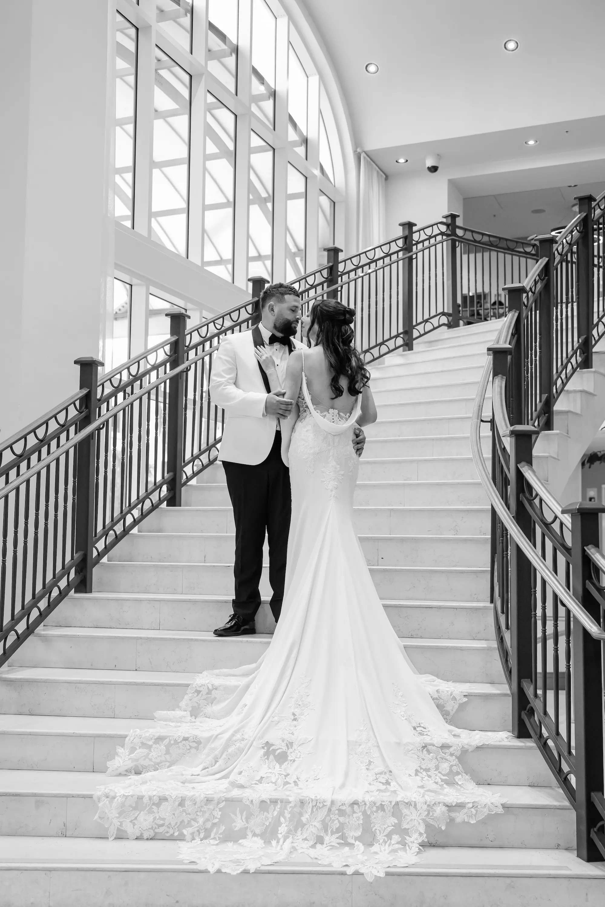 Black and White Bride and Groom Staircase Wedding Portrait | Elegant Intricate Lace Fit-and-Flare White Violet Grace Wedding Gown with Open, Draped Cowl Back Inspiration | St Pete Photographer Lifelong Photography Studio
