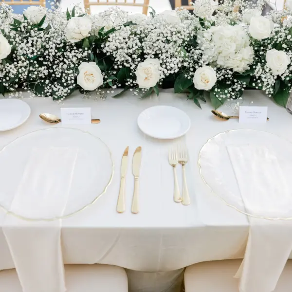 28Elegant Timeless Ivory and Green Garden Wedding - Romantic Outdoor St. Pete Wedding | Sunken Gardens Wedding Reception Table with White Linens and Clear Chargers with Gold Rims, Clear Napkins and Gold Flatware Ideas | White Roses and Baby's Breath Wedding Reception Decor Centerpiece Garland Inspiration | Tampa Bay Rentals Fiesta Solutions Event Rentals | Caterer Amici's Catered Cuisine