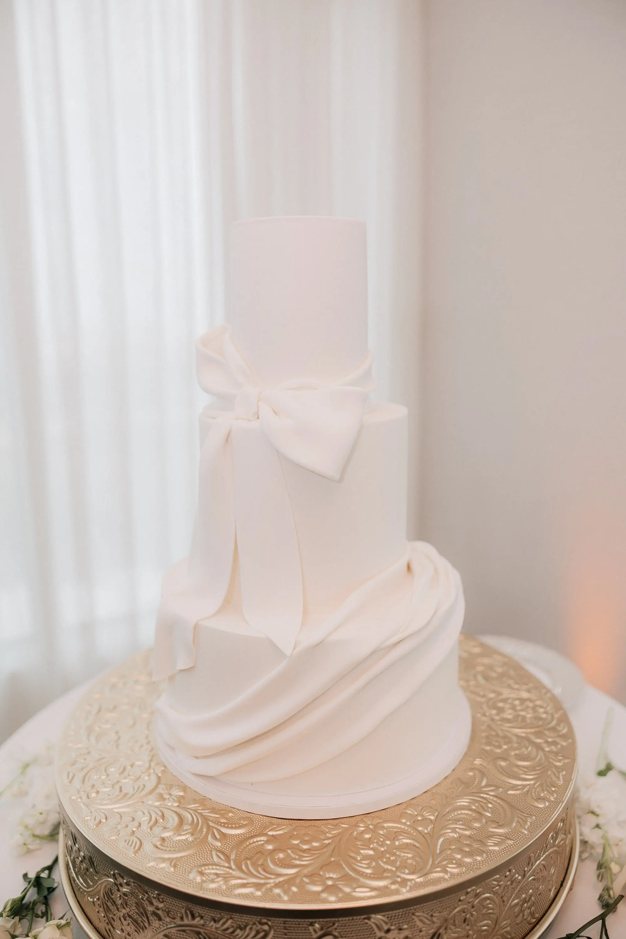 29Classic Gold and White Wedding Decor Inspiration - Classic, Ivory Rooftop Wedding | Grand Hyatt Tampa Bay Monochromatic Three Tier White Wedding Cake with White Bow Detail Inspiration | Gold Cake Stand Ideas