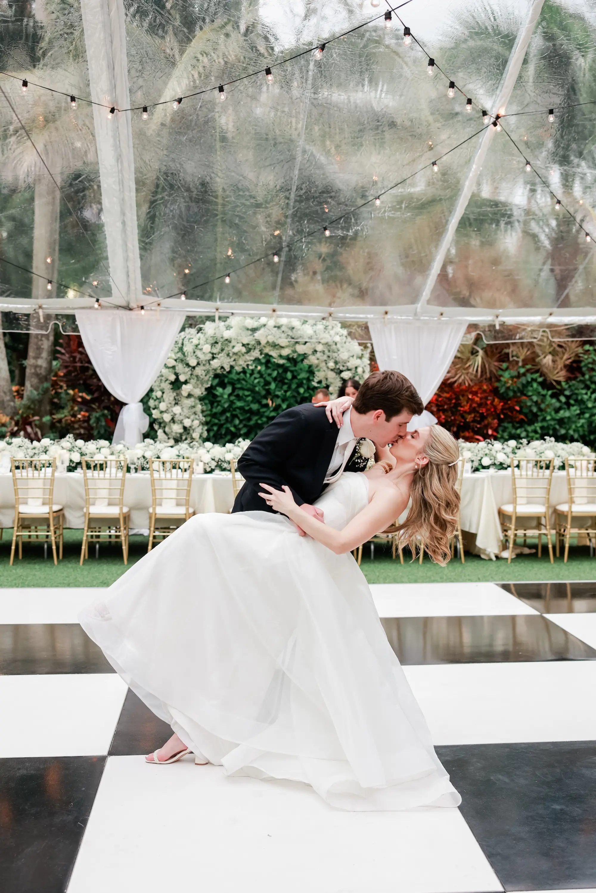 38Elegant Timeless Ivory and Green St Pete Wedding Venue Sunken Gardens - Romantic Outdoor St. Pete Wedding | Sunken Gardens Bride and Groom First Dance on White and Black Checkered Dance Floor Wedding Portrait | Outdoor Tented Wedding Reception with String Lights Decor Inspiration | Tampa Bay Rentals Fiesta Solutions Event Rentals | St Pete Photographer Lifelong Photography Studio | Venue Sunken Gardens