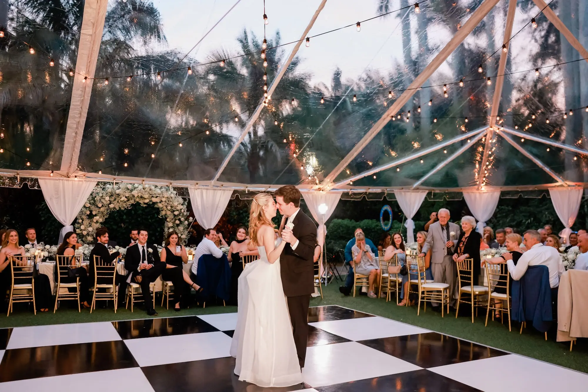 39Elegant Timeless Ivory and Green St Pete Wedding Venue Sunken Gardens - Romantic Outdoor St. Pete Wedding | Sunken Gardens Bride and Groom First Dance on White and Black Checkered Dance Floor Wedding Portrait | Outdoor Tented Wedding Reception with String Lights Decor Inspiration | Tampa Bay Rentals Fiesta Solutions Event Rentals | St Pete Photographer Lifelong Photography Studio | Venue Sunken Gardens