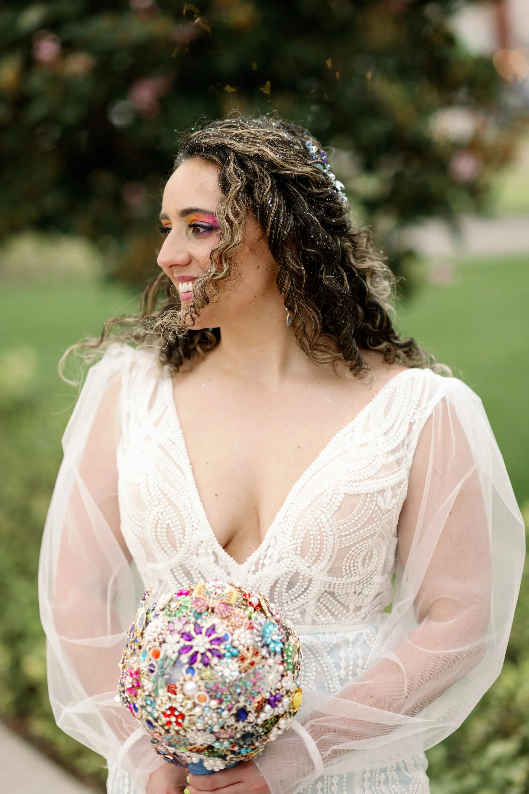 21Whimsical Rainbow Inspired Wedding Ideas - Whimsical, Vibrant Downtown Tampa Wedding | Armature Works Bride Wedding Portrait | Colorful Brooch Wedding Bridal Bouquet Inspiration | Elegant V-Neck White Magnolia White Wedding Gown with Long Lace Detailed Sleeves Ideas | Half Up Half Down Voluminous Curls Bridal Hair Inspiration | Vibrant Eyeshadow Ideas | Ybor Hair and Makeup Artist Adore Bridal Hair and Makeup | Tampa Bay Photographer Dewitt For Love Photography