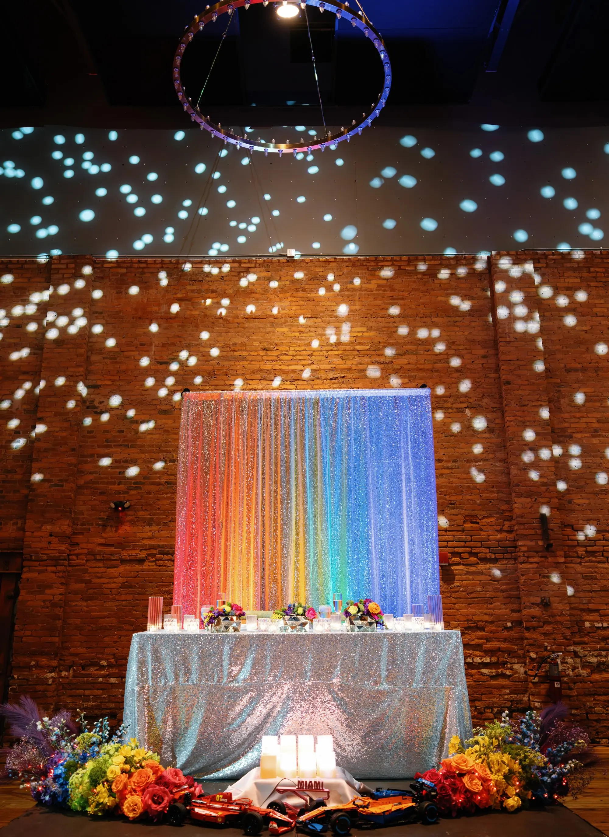 31Whimsical Rainbow Inspired Wedding Ideas Tampa Venue Armature Works - “Best Of” 2025: Wedding Receptions Part 2 Bright Colorful Rainbow Wedding Reception Sweetheart Table Decor Inspiration | Silver Sequined Table Cloth Ideas | Red, Orange, Yellow, Green, Blue, Indigo, Violet Flower Arrangement Reception Decor Inspiration | Over The Top Rental Linens | Event Planner Unique Weddings and Events | Industrial Tampa Wedding Venue Armature Works
