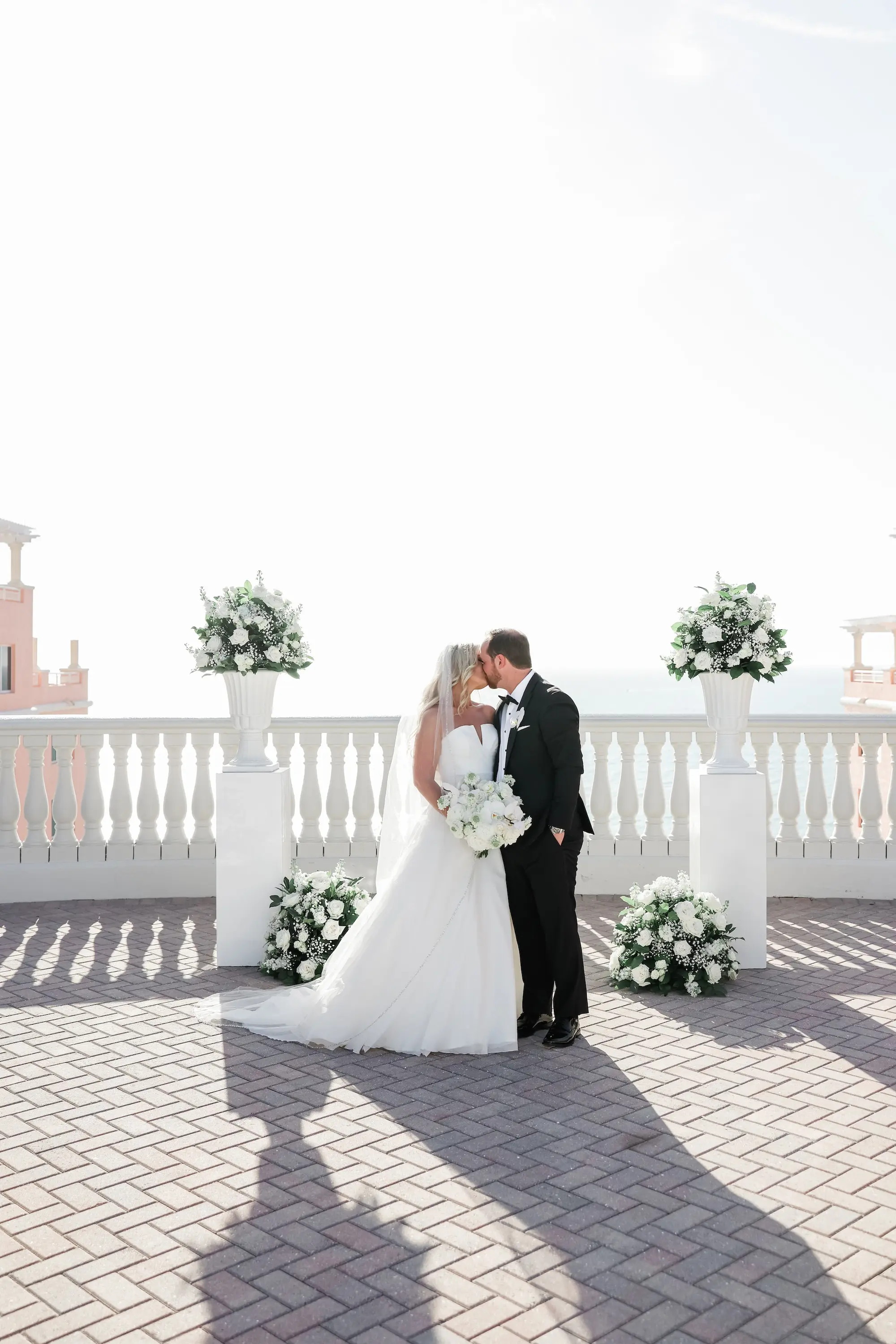 34Classic White Florida Wedding Ideas Venue Hyatt Clearwater Beach - Classic, White Rooftop Wedding | Hyatt Regency Clearwater Beach Bride and Groom Wedding Ceremony Balcony Oceanview Kissing Portrait | Monochromatic White Roses and Baby's Breath Flower Arrangement on White Columns Ceremony Decor Ideas | Tampa Bay Photographer Lifelong Photography Studio | Florida Wedding Venue Hyatt Regency Clearwater Beach Resort and Spa