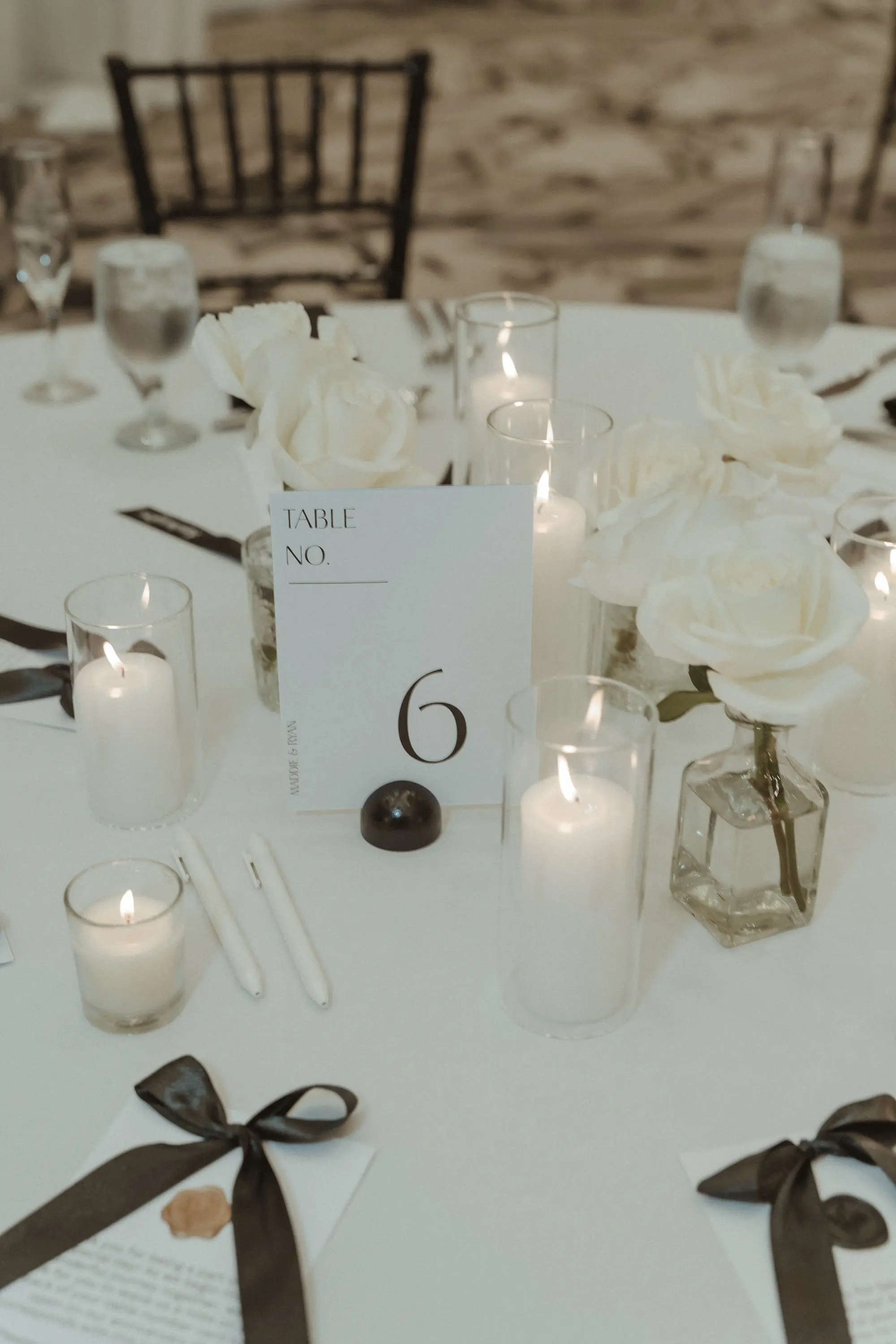 34Sophiscated Black and White Wedding Inspiration - “Best Of” 2025: Wedding Receptions Part 2 Formal Classic Black and White Wedding Reception Decor Ideas | White Table Linens with White Menus and Black Bows Tablescape Decor Inspiration | Romantic Candles and Single Stem White Roses in Bud Vases Centerpiece Decor Ideas | Tampa Bay Planner The Olive Tree Weddings