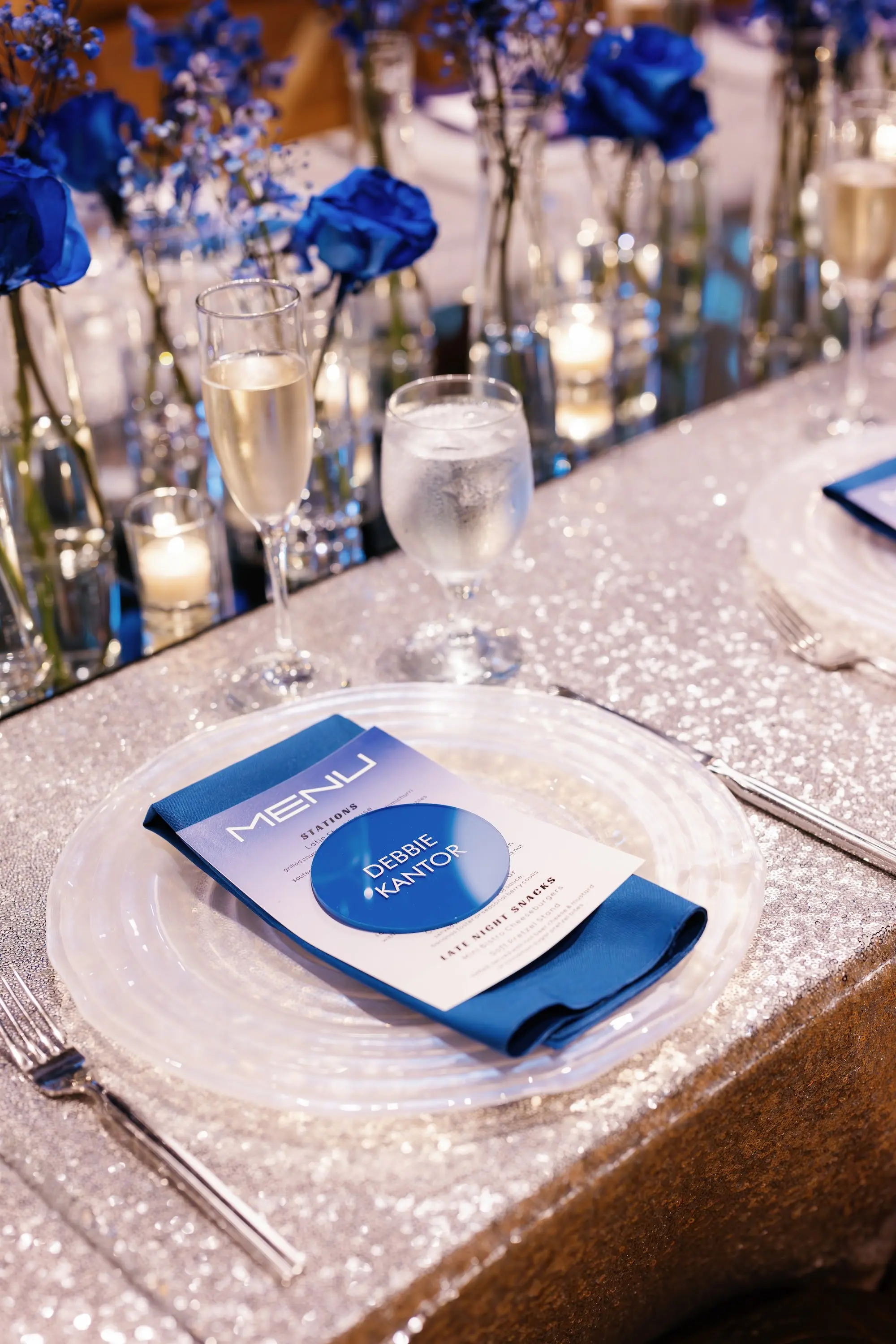 34Whimsical Rainbow Inspired Wedding Ideas - “Best Of” 2025: Wedding Receptions Part 2 Bright Colorful Rainbow Wedding Reception Decor Inspiration | Silver Sequined Table Cloth with Clear Charger and Blue Menu, Napkin and Name Card Tablescape Ideas | Tabletop Rentals A Chair Affair | Over The Top Rental Linens | Event Planner Unique Weddings and Events