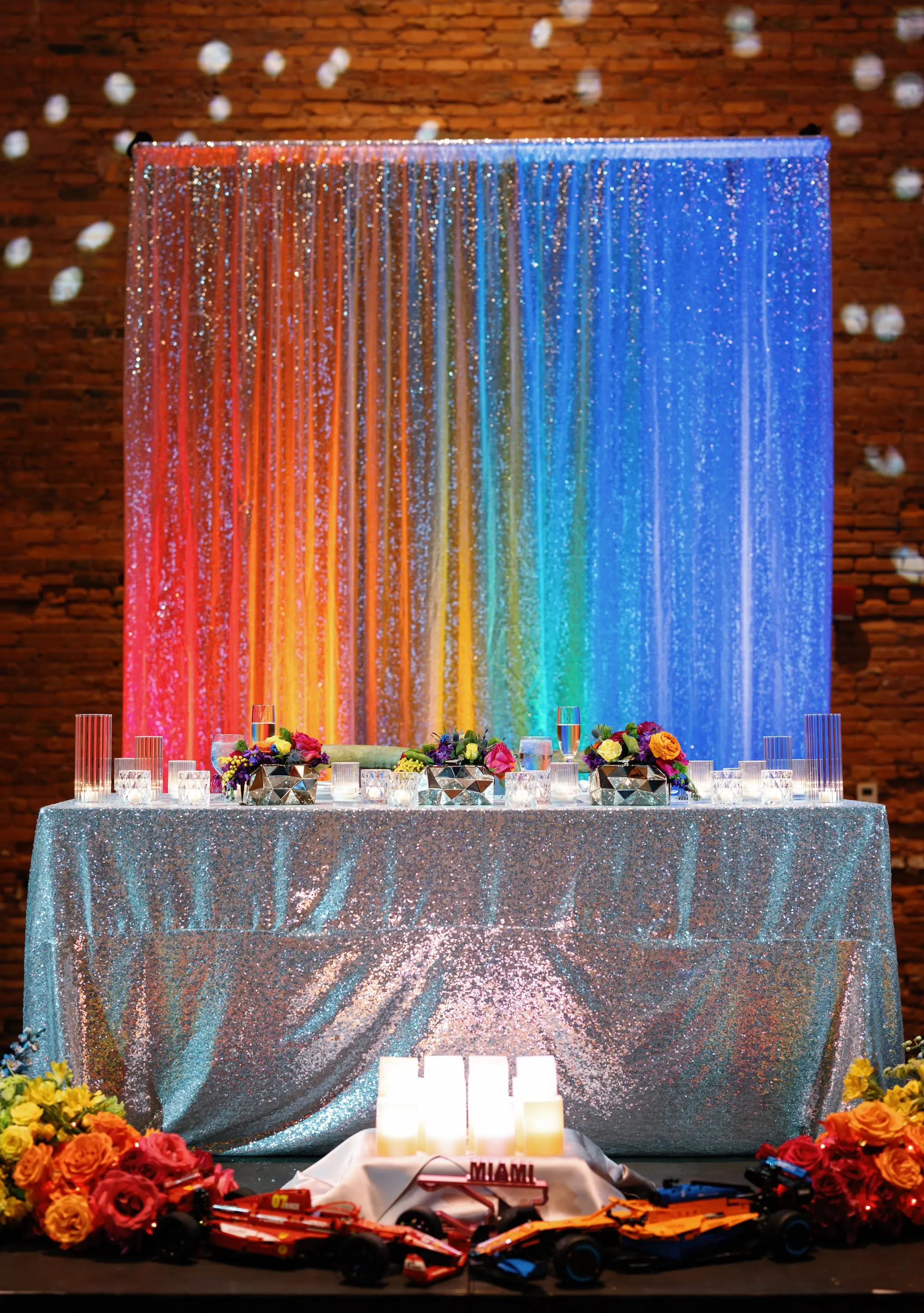 39Whimsical Rainbow Inspired Wedding Ideas - “Best Of” 2025: Wedding Receptions Part 2 Bright Colorful Rainbow Wedding Reception Sweetheart Table Decor Inspiration | Silver Sequined Table Cloth Ideas | Red, Orange, Yellow, Green, Blue, Indigo, Violet Flower Arrangement Reception Decor Inspiration | Over The Top Rental Linens | Event Planner Unique Weddings and Events | Industrial Tampa Wedding Venue Armature Works