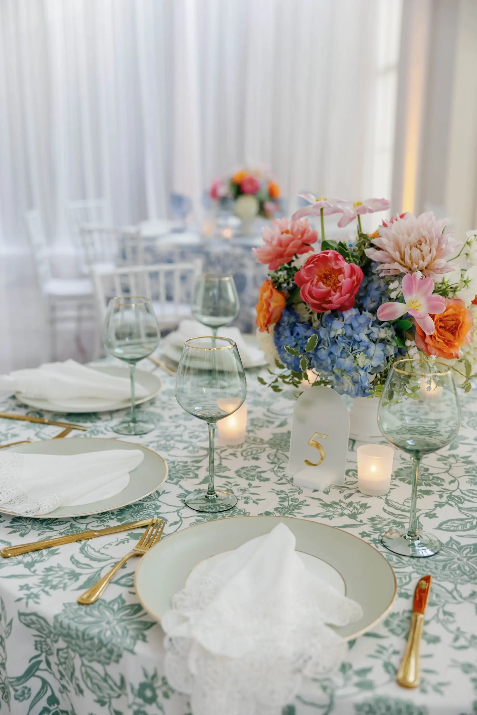 47European Inspired Blue and Green Wedding Inspiration - “Best Of” 2025: Wedding Receptions Part 2 European Inspired Wedding Reception Tablescape Decor Ideas | Green Floral Detailed Tablecloths with Light Green, White and Gold Chargers and Gold Flatware Ideas | Light Green Colored Glassware Decor Ideas | Pink, Orange, Peach, Coral, Light Pink, Blue Floral Arrangement Centerpieces Inspiration | Acrylic Clear and Gold Table Numbers Ideas | Florist Monarch Events and Design | Kate Ryan Event Rentals