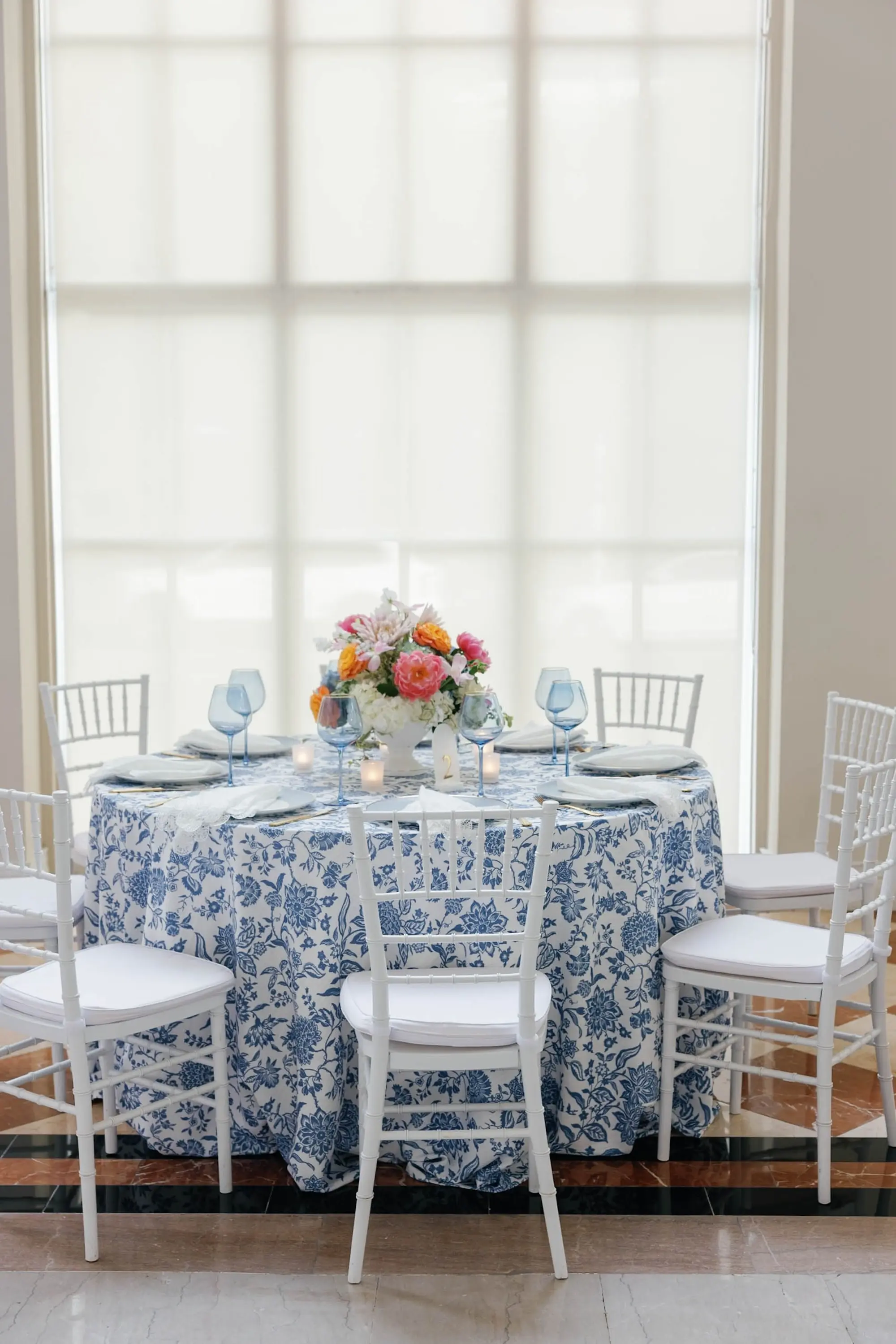 49European Inspired Blue and Green Wedding Inspiration - “Best Of” 2025: Wedding Receptions Part 2 European Inspired Wedding Reception Decor Ideas | Floral Detailed Blue Tablecloths with Light Blue Colored Glassware Inspiration | White Chiavari Wedding Reception Chairs Ideas | Pink, Orange, Peach, Coral, Light Pink, Blue Floral Arrangement Centerpieces Inspiration | Florist Monarch Events and Design | Kate Ryan Event Rentals