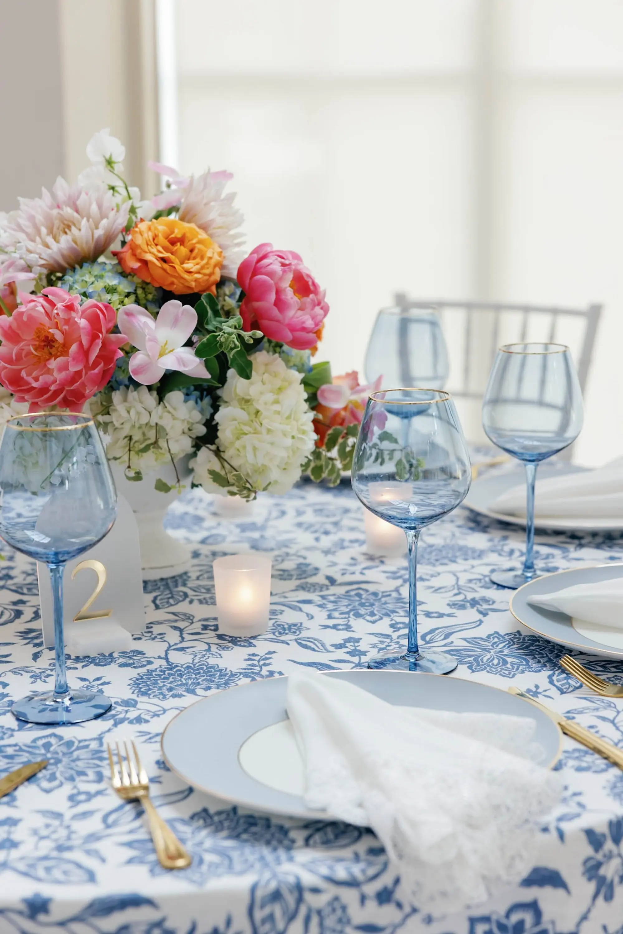 50European Inspired Blue and Green Wedding Inspiration - “Best Of” 2025: Wedding Receptions Part 2 European Inspired Wedding Reception Decor Ideas | Floral Detailed Blue Tablecloths with Light Blue Colored Glassware Inspiration | White Chiavari Wedding Reception Chairs Ideas | Pink, Orange, Peach, Coral, Light Pink, Blue Floral Arrangement Centerpieces Inspiration | Florist Monarch Events and Design | Kate Ryan Event Rentals