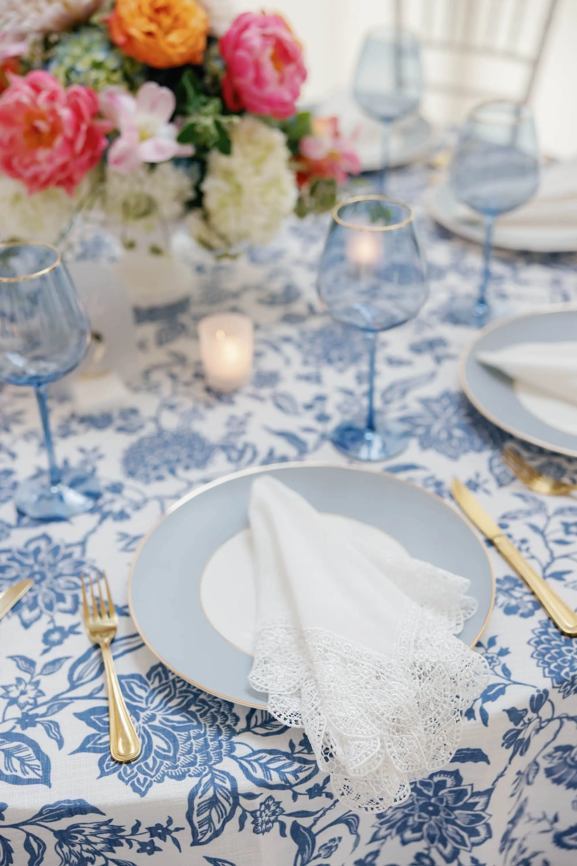 51European Inspired Blue and Green Wedding Inspiration - “Best Of” 2025: Wedding Receptions Part 2 European Inspired Wedding Reception Decor Ideas | Floral Detailed Blue Tablecloths with Light Blue Colored Glassware and Light Blue and Gold Chargers with Gold Flatware Tablescape Inspiration | White Chiavari Wedding Reception Chairs Ideas | Pink, Orange, Peach, Coral, Light Pink, Blue Floral Arrangement Centerpieces Inspiration | Florist Monarch Events and Design | Kate Ryan Event Rentals
