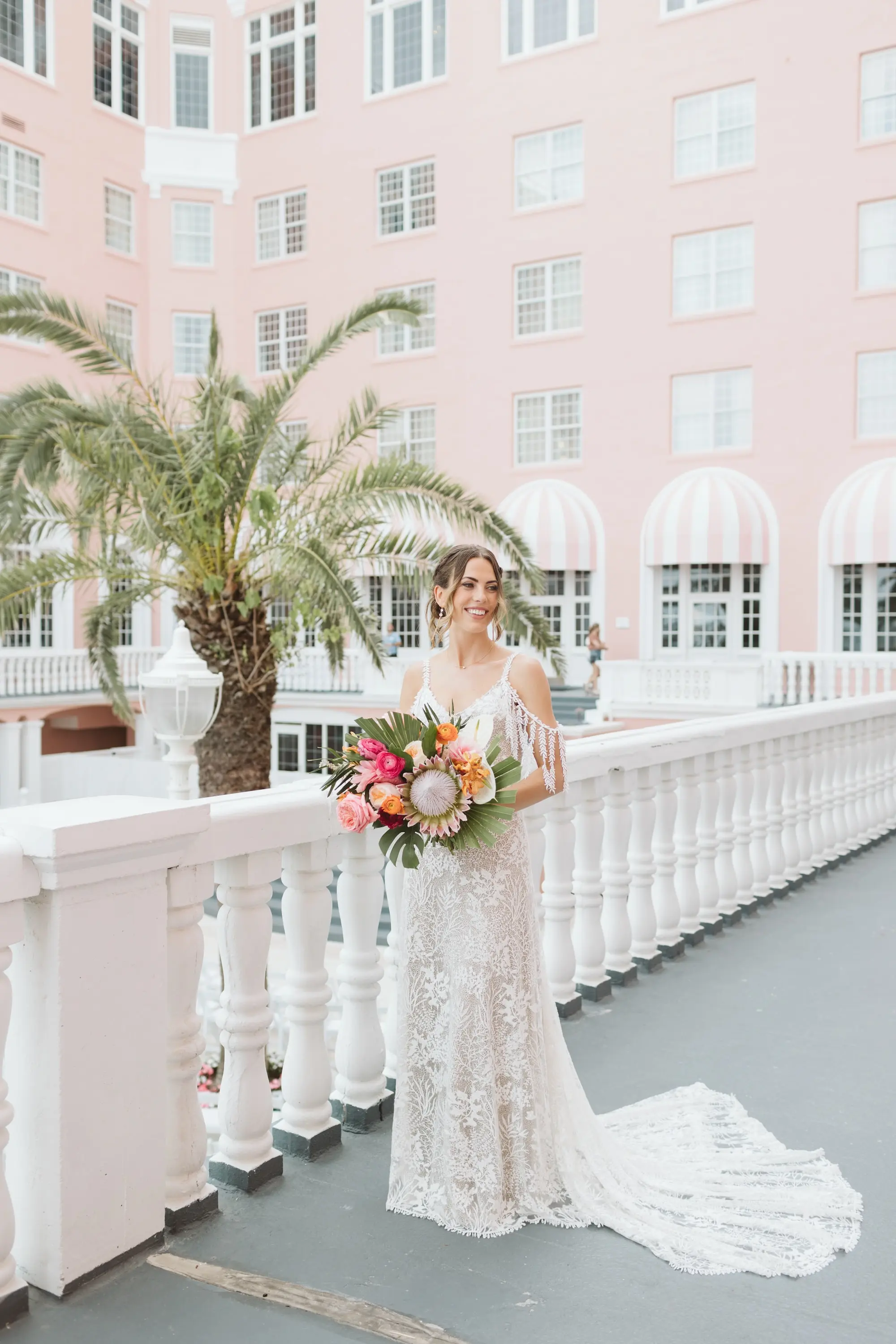 10Tropical Beach Boho Pink and Orange Wedding Inspiration St Pete Venue The Don CeSar - Vibrant, Tropical Boho St. Pete Beach Wedding | The Don CeSar Bride Wedding Portrait | Low Bun with Loose Curls Boho Wedding Hairstyle Inspiration | Natural Beauty Wedding Makeup Ideas | Romantic Bohemian Grace Loves Lace Wedding Gown with Detailed Floral Lace and Off-the-Shoulder Tasseled Armbands Inspiration | Boho Tropical Pink, Orange, Red, White with Large Palm Fronds Floral Bouquet Ideas | Tampa Bay Hair and Makeup Artist Femme Akoi Beauty Studio