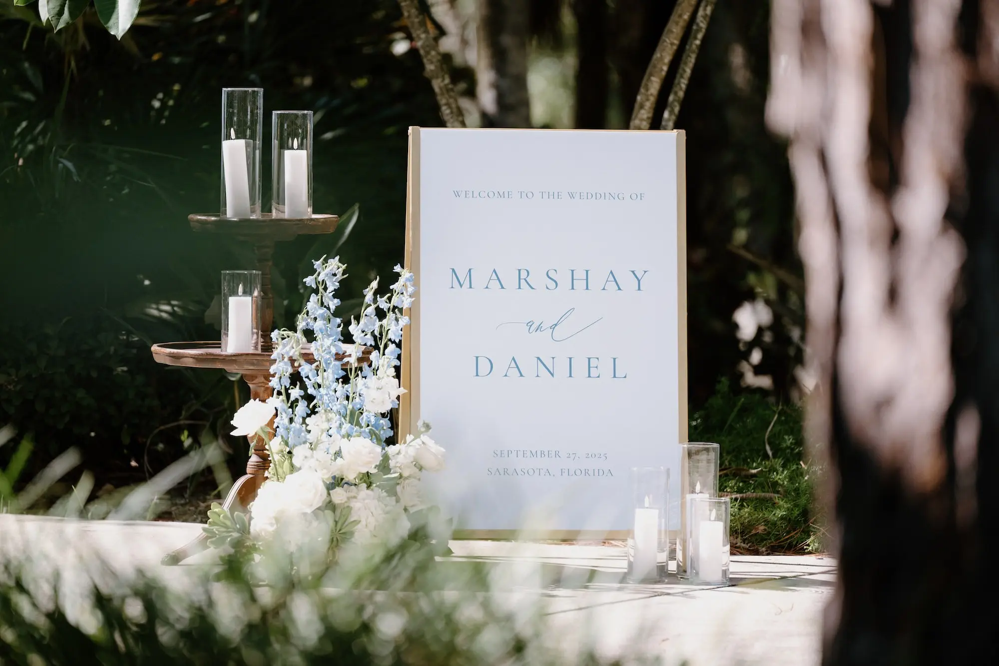 Elegant White and Blue Fall Florida Wedding Inspiration | White Wedding Reception Signage with Blue Writing Ideas | White Roses and Florals with Blue Delphiniums with White Candles in Glass Vases Wedding Reception Decor Inspiration | Sarasota Florist Beneva Flowers