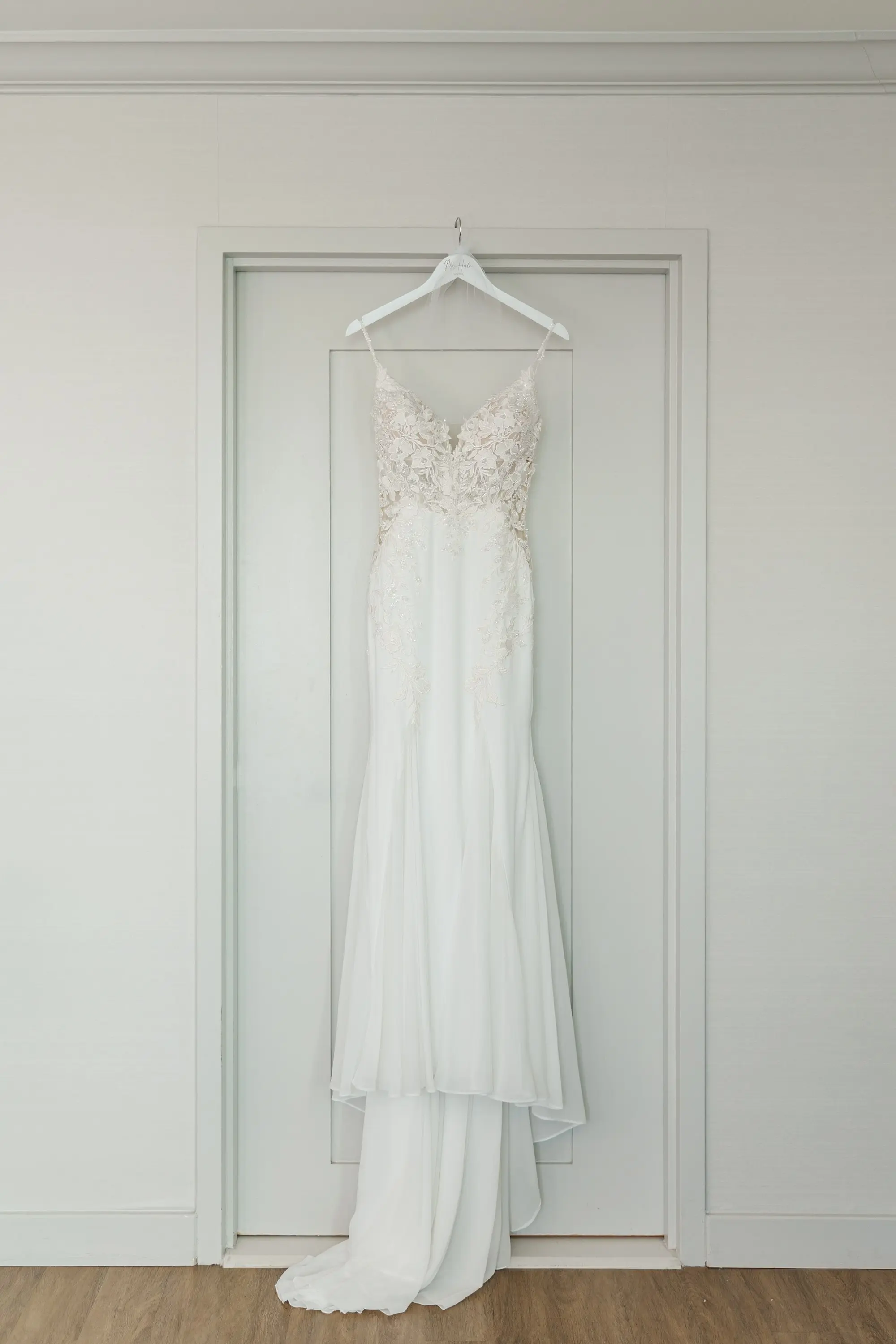 2Classic Emerald Green and Champagne Wedding Inspiration - Classic Emerald Green Downtown Tampa Wedding | Bob Buckhorn Center Romantic White Enzoani Wedding Gown with Lace Floral Detailed Bodice, Sweetheart Neckline and Delicate Spaghetti Straps Hanging from White Hanger | Tampa Bay Photographer Mary Anna Photography