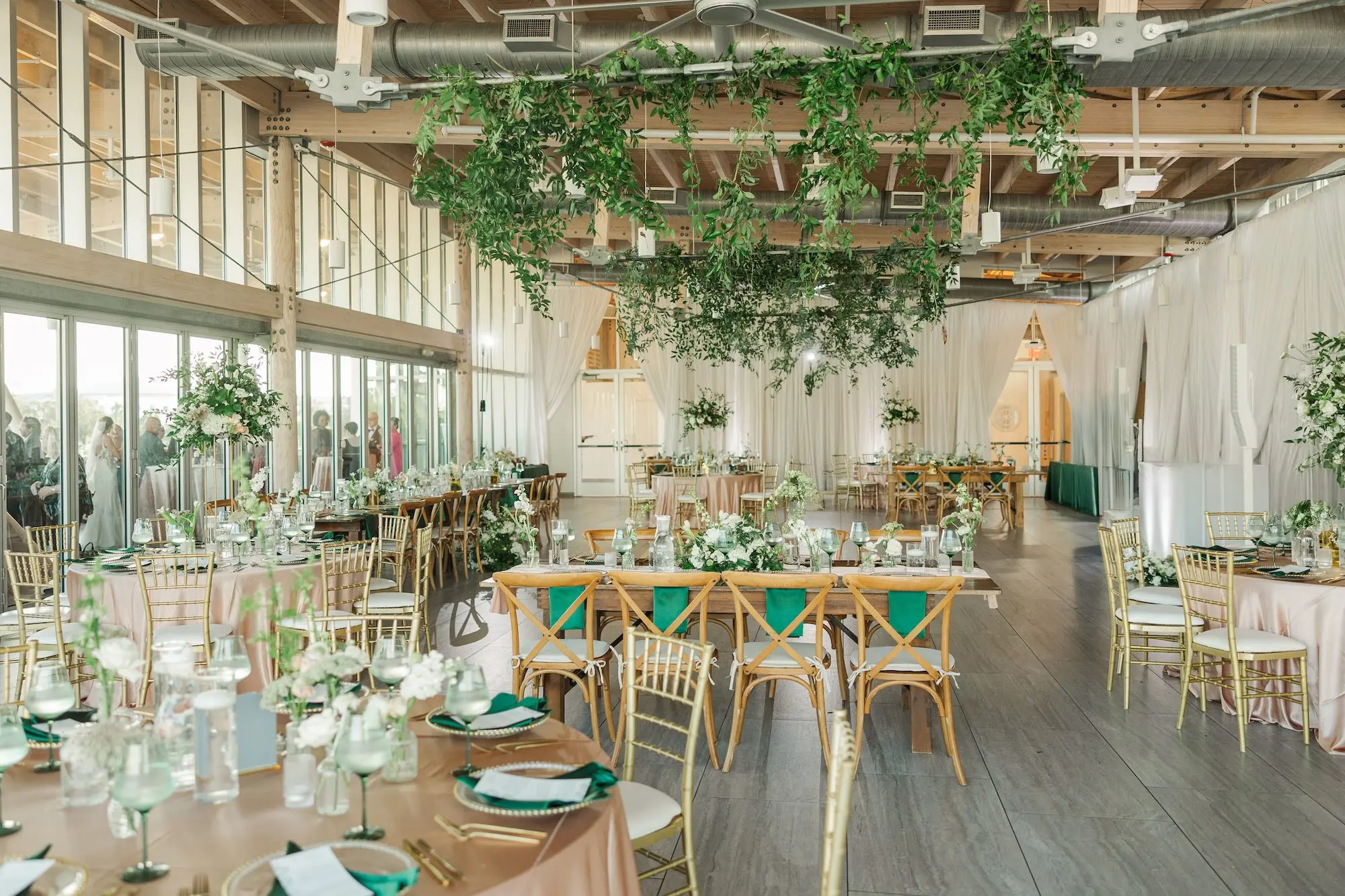39Classic Emerald Green and Champagne Wedding Inspiration Bob Buckhorn Tampa River Center Venue - Classic Emerald Green Downtown Tampa Wedding | Bob Buckhorn Center Elegant Riverfront Ballroom Wedding Reception | Rustic Wooden Chairs at Long Wooden Feasting Table | Short Centerpieces with White Hydrangeas, Roses, Wisteria Flower and Palm Greenery Arrangement Ideas | Emerald Green Napkins Tablescape Decor Inspiration | Eucalyptus Greenery Hanging Ceiling Decor Ideas | Tampa Bay Planner Wilder Mind Events | Venue Tampa River Center