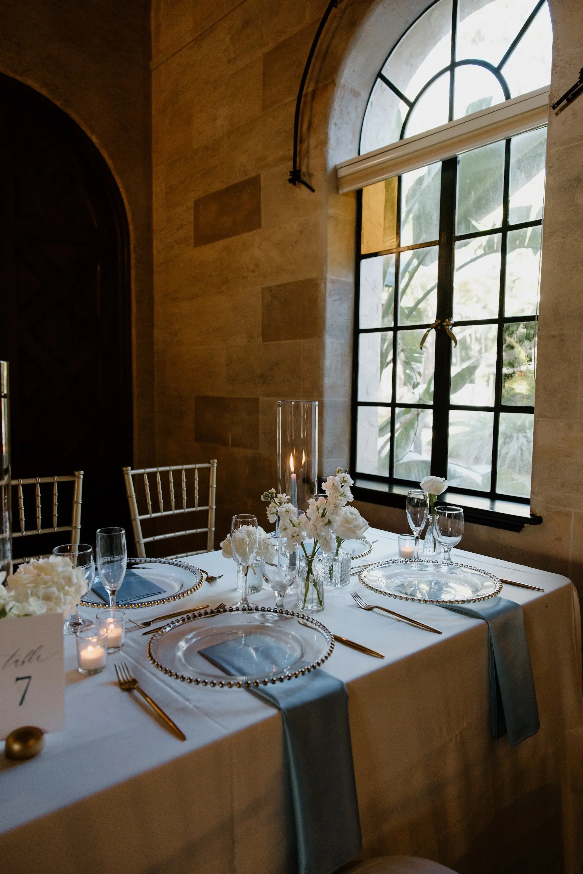 Classic Ballroom Wedding Reception | Modern Gold Chiavari Chairs | Bud Vase Centerpiece White Roses and Orchid Flower Arrangement Ideas | Clear Chargers with Gold Rims and Satin Light Blue Napkins Wedding Reception Tablescape Decor Inspiration | Sarasota Florist Beneva Flowers | Venue Powel Crosely Estate