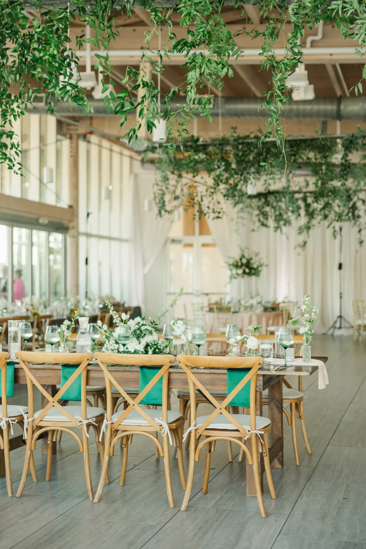 42Classic Emerald Green and Champagne Wedding Inspiration Bob Buckhorn Tampa River Center Venue - Classic Emerald Green Downtown Tampa Wedding | Bob Buckhorn Center Elegant Riverfront Ballroom Wedding Reception | Rustic Wooden Chairs at Long Wooden Feasting Table | Short Centerpieces with White Hydrangeas, Roses, Wisteria Flower and Palm Greenery Arrangement Ideas | Emerald Green Napkins Tablescape Decor Inspiration | Eucalyptus Greenery Hanging Ceiling Decor Ideas | Tampa Bay Planner Wilder Mind Events | Venue Tampa River Center