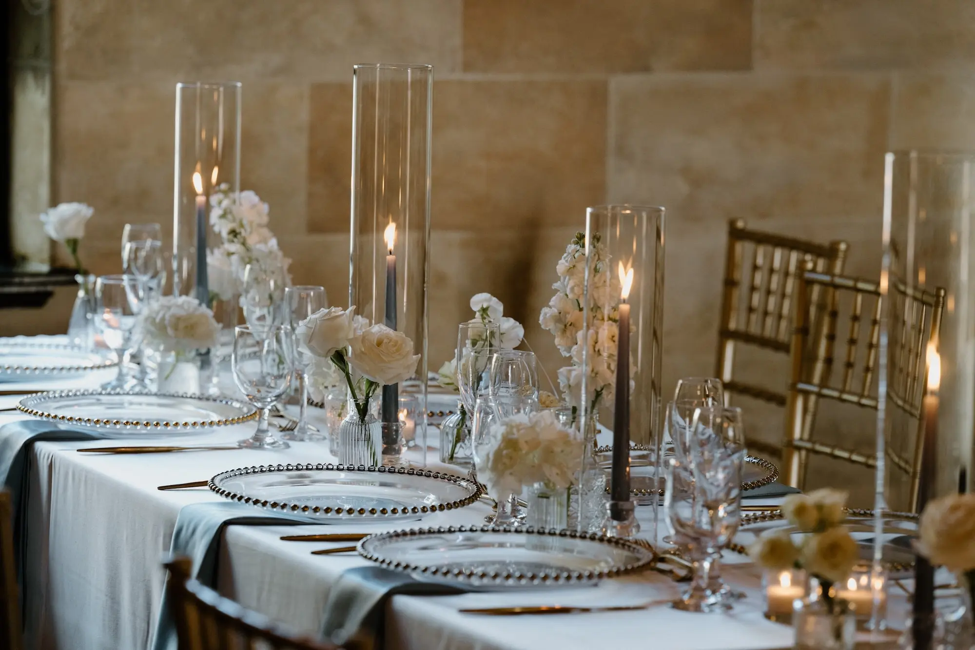 Classic Ballroom Wedding Reception | Modern Gold Chiavari Chairs | Bud Vase Centerpiece White Roses and Orchid Flower Arrangement Ideas | Clear Chargers with Gold Rims and Satin Light Blue Napkins Wedding Reception Tablescape Decor Inspiration | Blue Taper Candles in Vase Glasses Decor Ideas | Sarasota Florist Beneva Flowers | Venue Powel Crosely Estate