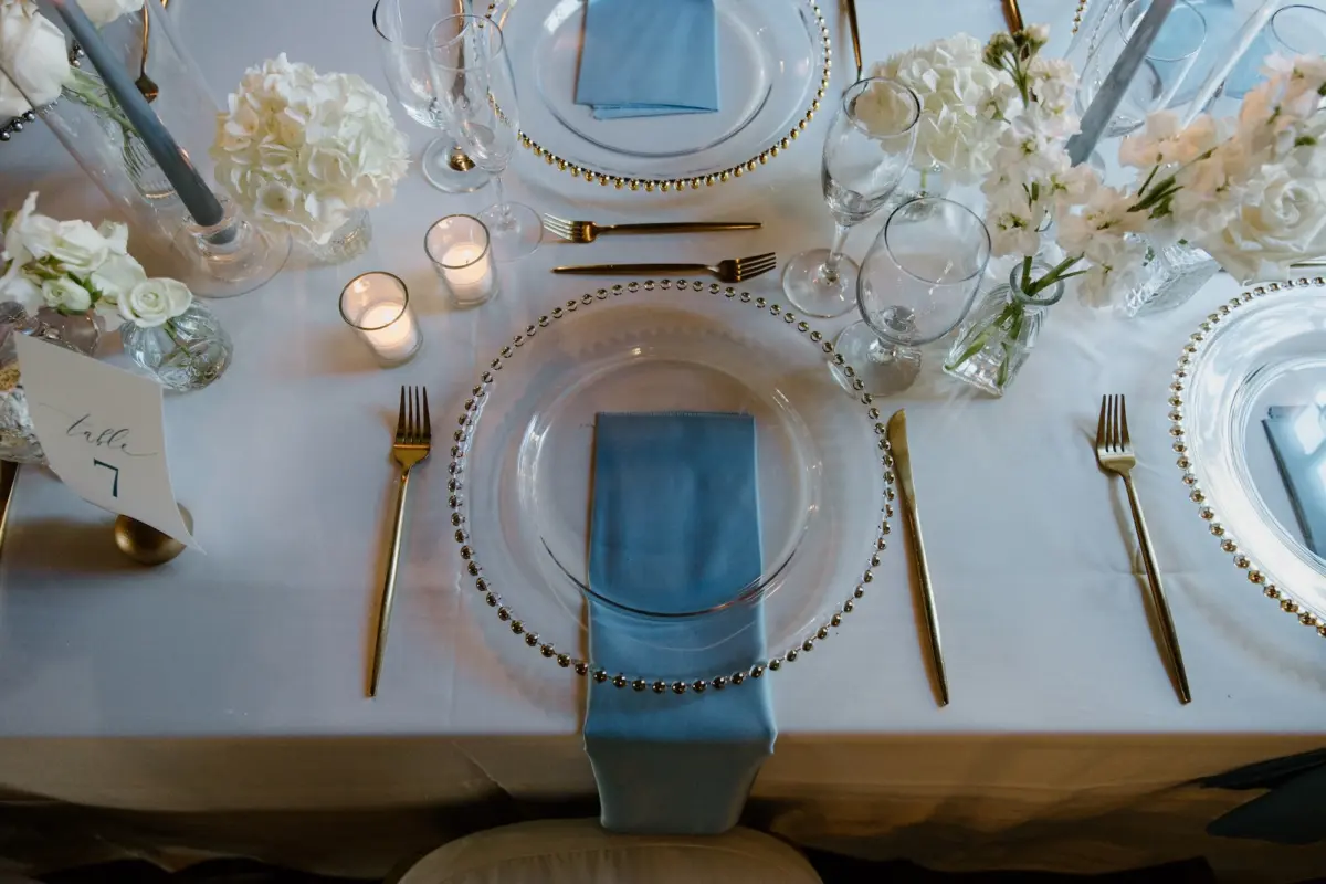 Classic Ballroom Wedding Reception | Modern Gold Chiavari Chairs | Bud Vase Centerpiece White Roses and Orchid Flower Arrangement Ideas | Clear Chargers with Gold Rims and Satin Light Blue Napkins Wedding Reception Tablescape Decor Inspiration | Sarasota Florist Beneva Flowers | Venue Powel Crosely Estate