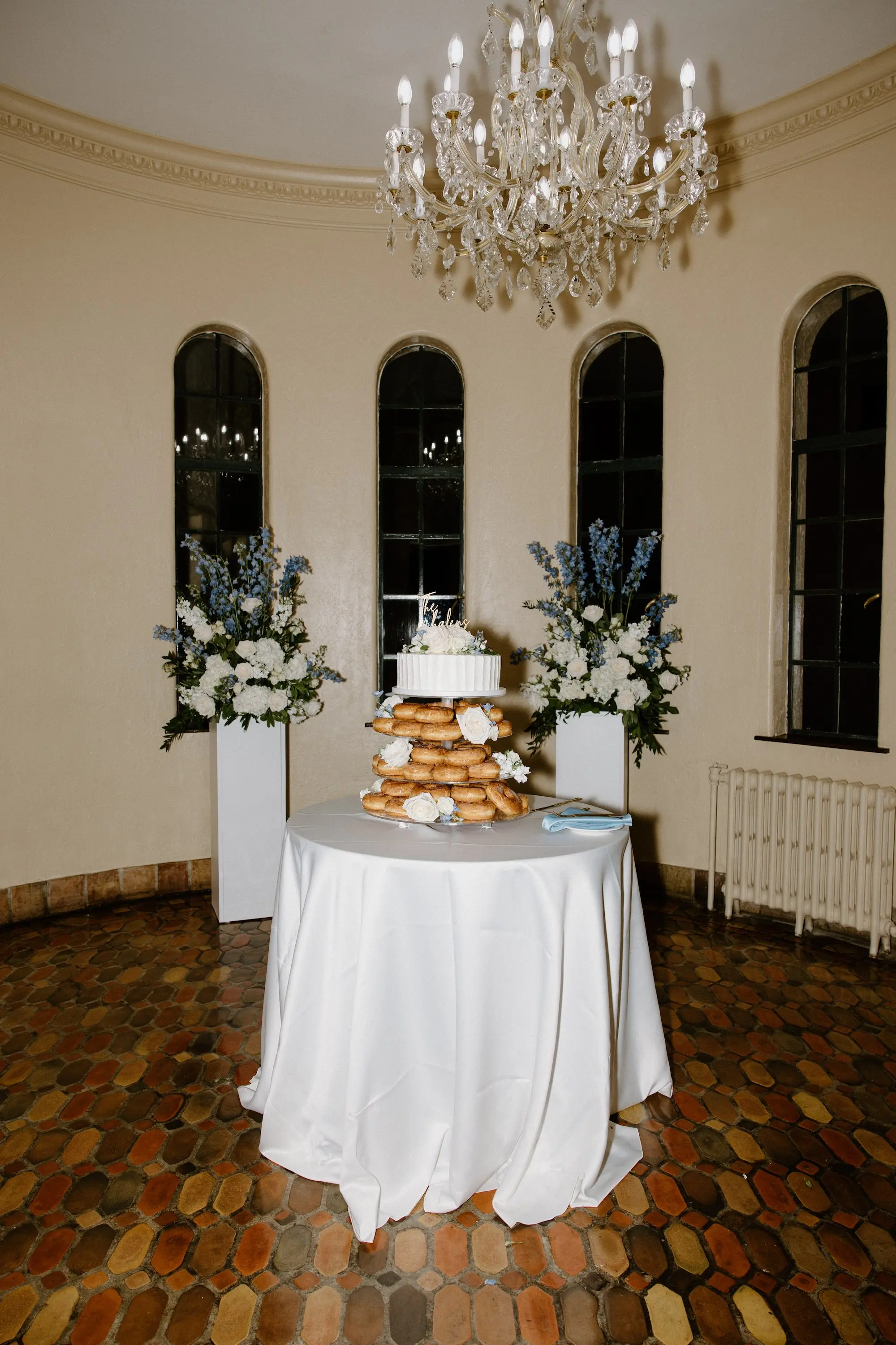 Donut Tower Wedding Cake Inspiration | White Roses and Florals with Blue Delphiniums on White Pedestals Wedding Reception Floral Arrangement Decor Ideas | Sarasota Florist Beneva Flowers