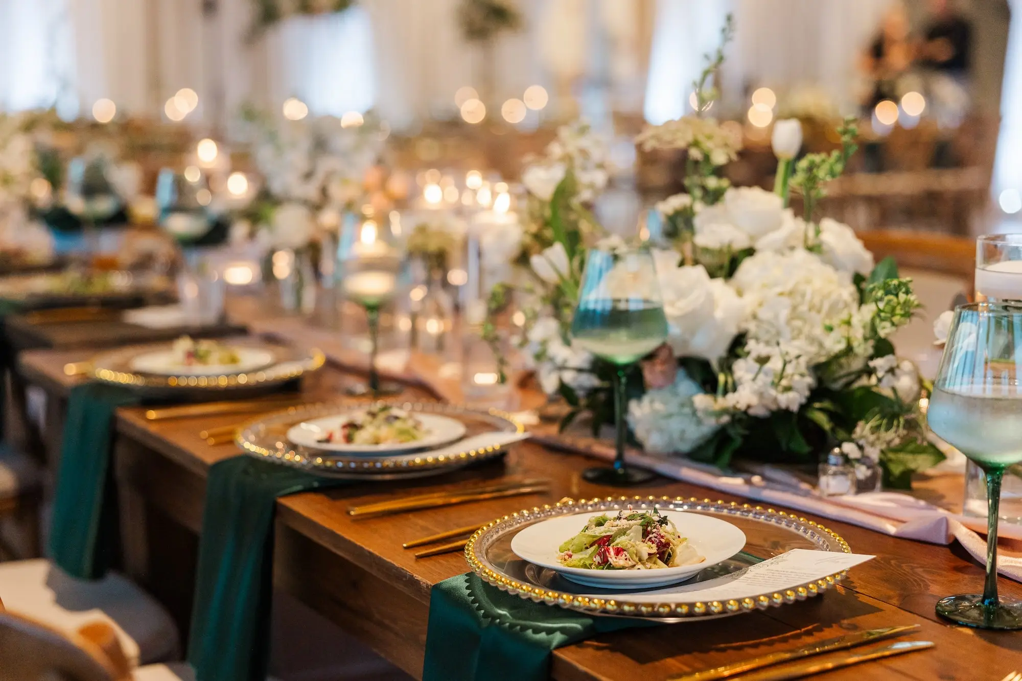 51Classic Emerald Green and Champagne Wedding Inspiration - “Best Of” 2025: Wedding Receptions Part 2 Romantic Riverfront Ballroom Wedding Reception | Gold Chiavari Chairs | Tall Gold Platform Centerpieces with White Hydrangeas, Roses, Wisteria Flower and Palm Greenery Arrangement Ideas | Clear Chargers with Gold Scalloped Edges and Emerald Green Napkins Tablescape Decor Inspiration | Tampa Bay Planner Wilder Mind Events | Florida Elite Events Catering | Venue Tampa River Center