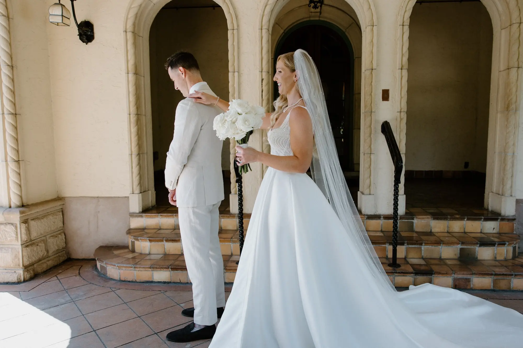 Bride and Groom First Look Wedding Portrait | White Pearl Corset Milla Nova Wedding Gown with Satin Skirt Inspiration | Monochromatic White Roses Bridal Bouquet Ideas | Hollywood Glam Curled Waves Wedding Bridal Hair Inspiration | Natural Glam Makeup Ideas | Sarasota Florist Beneva Flowers | Tampa Bay Boutique Truly Forever Bridal | Sarasota Hair and Makeup Artist Femme Akoi Beauty Studio | Content Creator Behind T