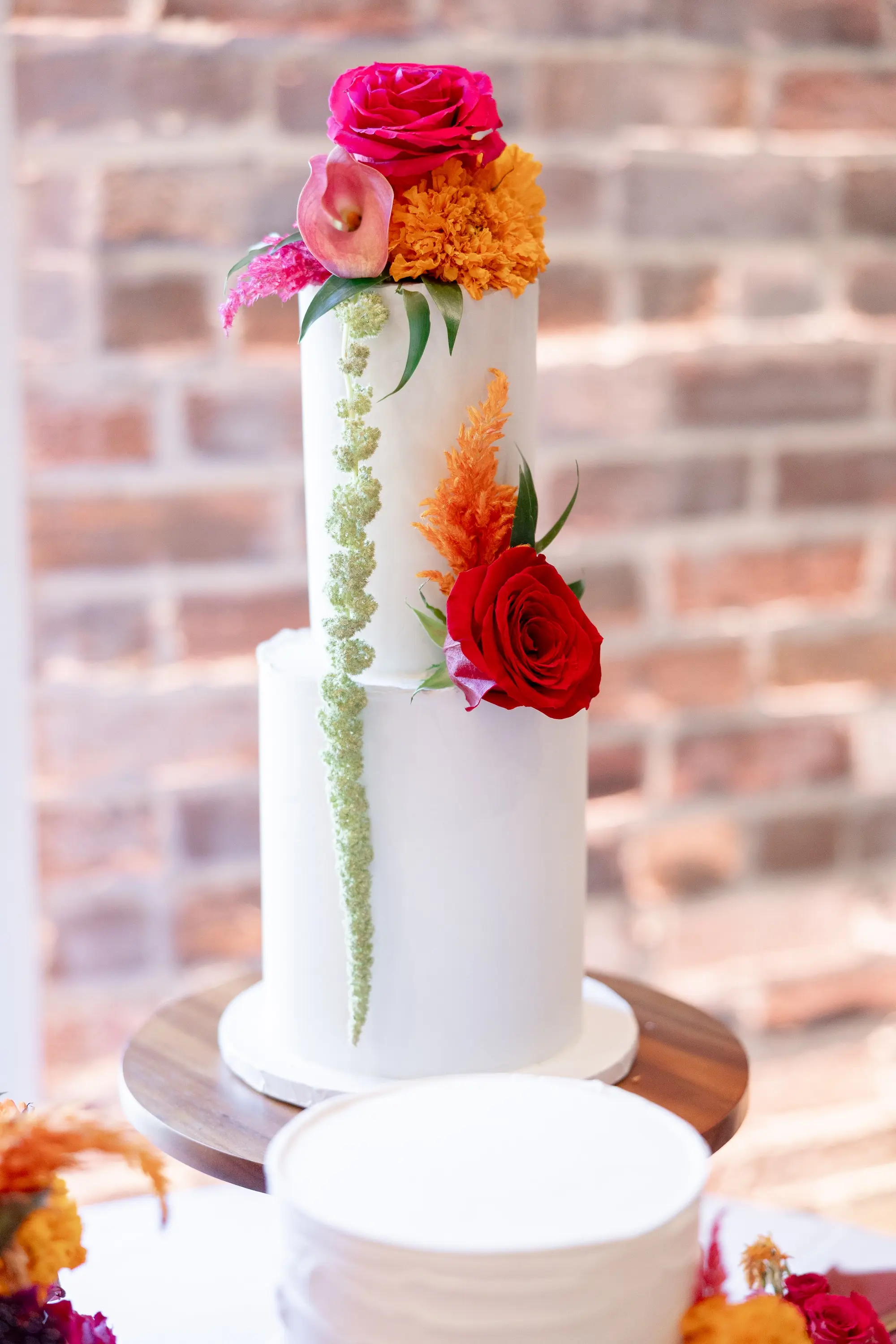 45Vibrant Southwestern Terracotta Pink and Orange Wedding Ideas - Vibrant, Rooftop Wedding Inspiration Shoot | Red Mesa Events Two Tier White Wedding Cake with Vibrant Pink and Red Roses, Yellow Orange Marigolds and Tropical Greenery Inspiration | Tampa Bay Florist Save The Date Florida | St Pete Event Planner Coastal Coordinating