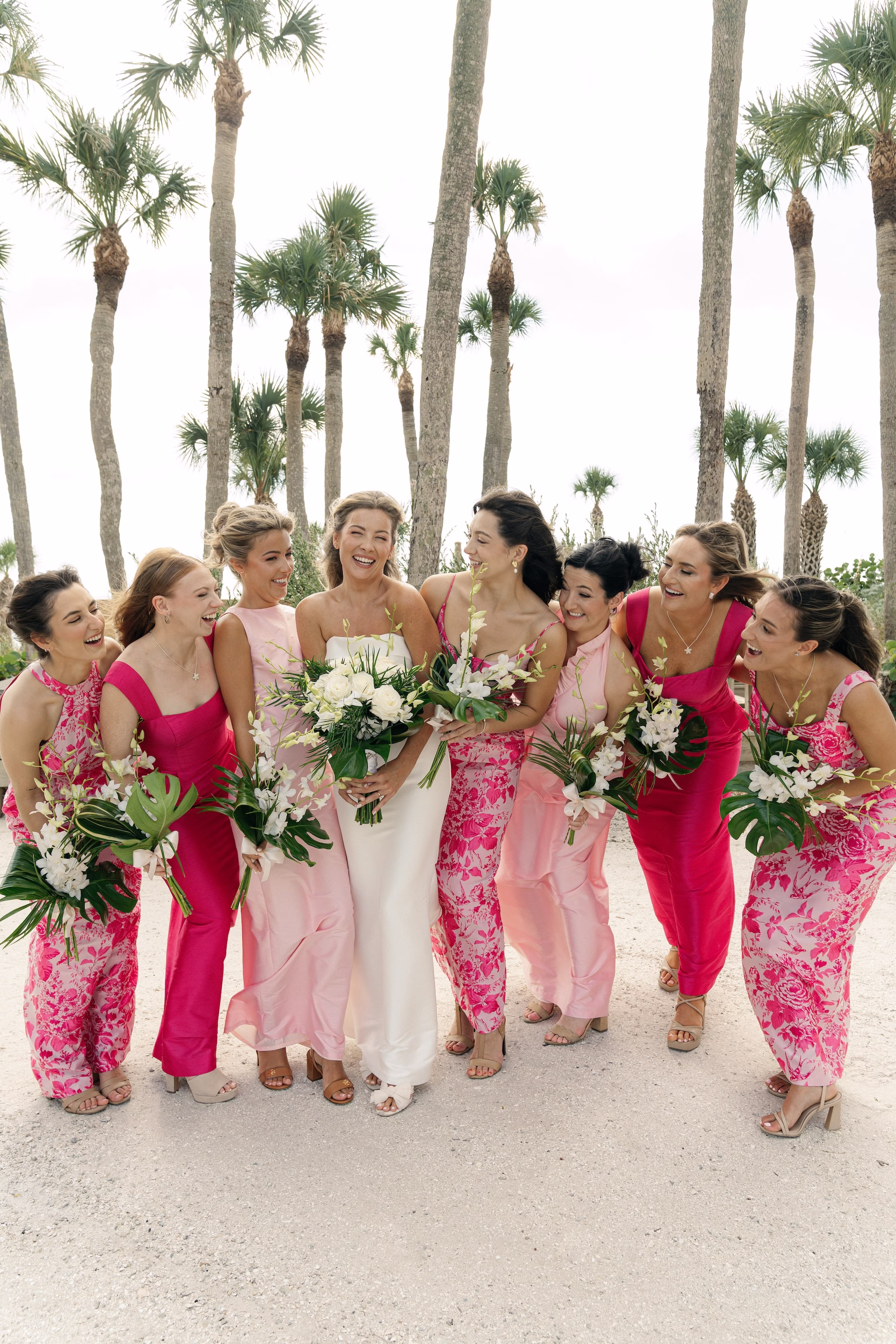 Bride and Bridesmaid Beach Wedding Portrait | Different Style Pink Bridesmaid Gowns Inspiration | White Florals and Tropical Green Palm Fronds Bridal Bouquet Ideas