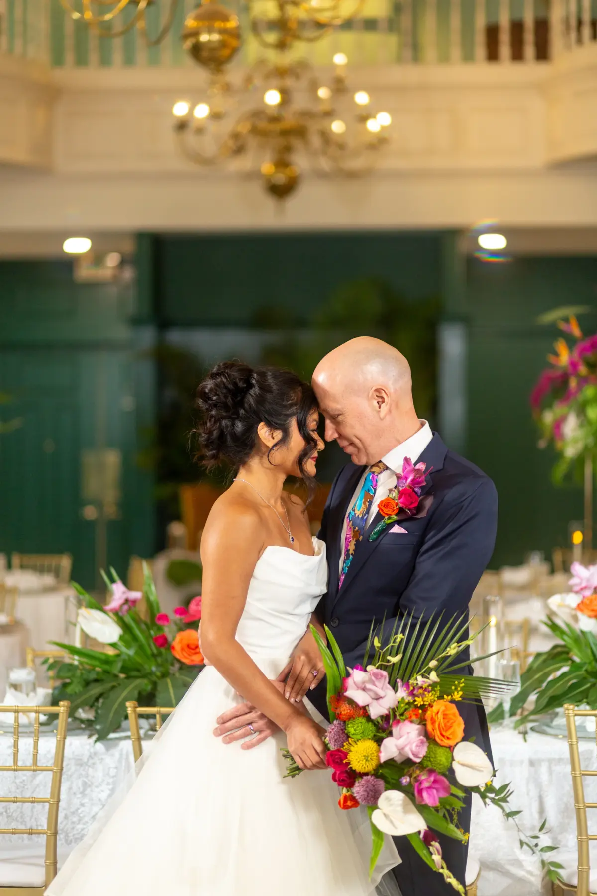 Bride and Groom Wedding Reception Portrait | Vivid Bright Tropical orange, Pink, Fuchsia, Yellow and White Orchids, Anthuriums and Roses with Lush Tropical Greenery Palms Bridal Bouquet Inspiration | White Strapless Wedding Ballgown with Sweetheart Neckline and Full Layered Tulle Skirt Ideas | Tampa Bay Boutique Truly Forever Bridal