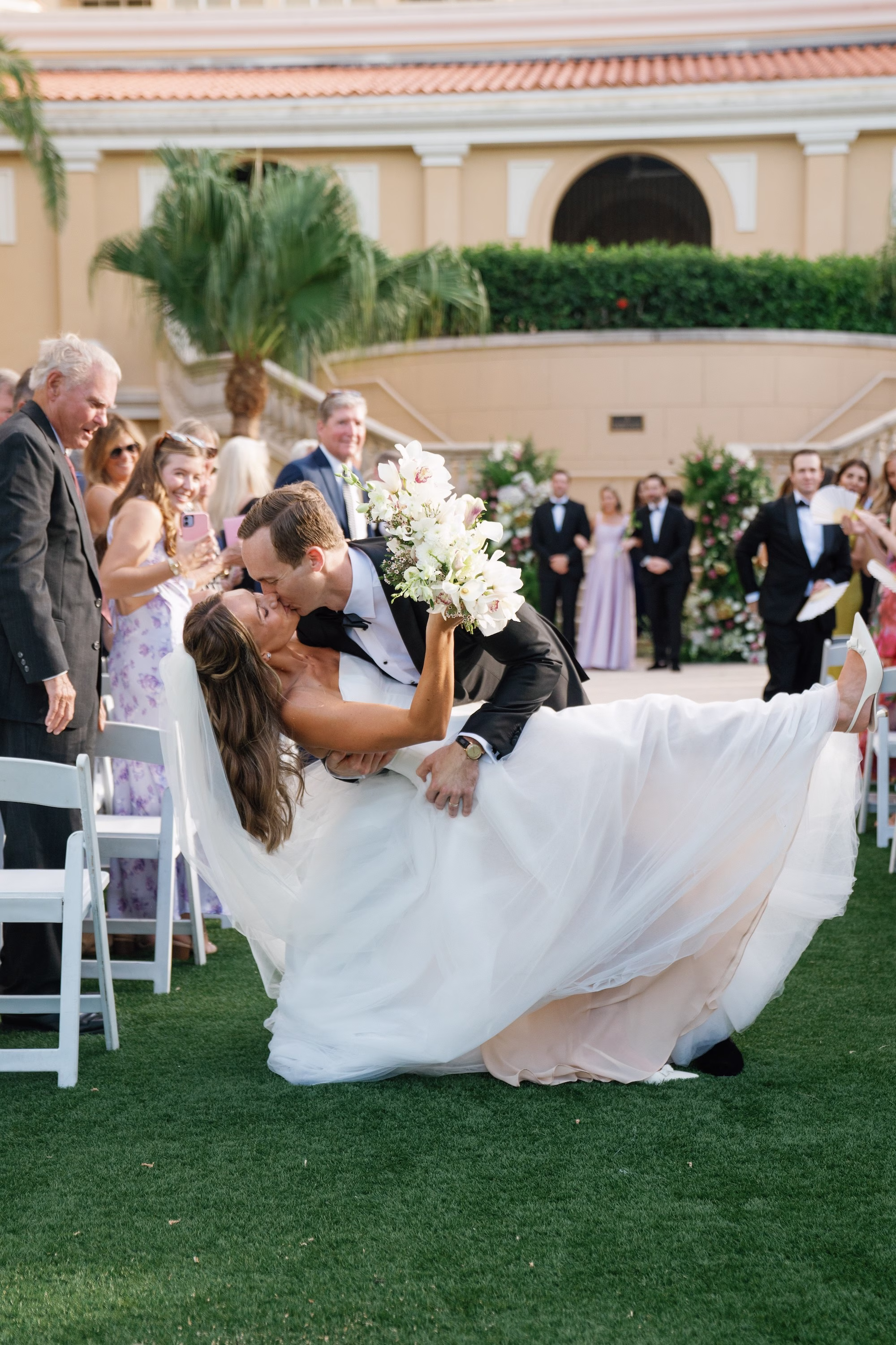 24Elegant Florida Garden Party Wedding Inspiration - Luxurious Garden Destination Wedding | Ritz-Carlton, Sarasota Bride and Groom Just Married Kissing Wedding Ceremony Aisle Wedding Portrait | Elegant Outdoor Lawn Wedding Ceremony with White Garden Chairs Inspiration | Luxury Wedding Venue The Ritz-Carlton Sarasota