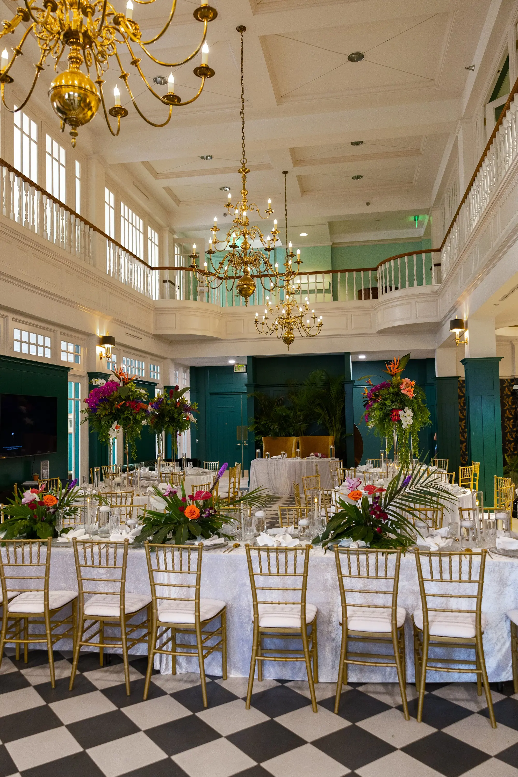Modern Classic Wedding Ideas | Black and White Checkered Reception Floor Inspiration | White Linens with Gold Chiavari Chairs Ideas | Bright Jewel Toned Coral, Mauves and White Tropical Floral Centerpieces with Deep Green Palms and Greenery Decor Inspiration | Clear Glass Chargers with Gold Rims and Gold Flatware Tablescape Decor Ideas | Tampa Bay Wedding Venue The Spiral Staircase