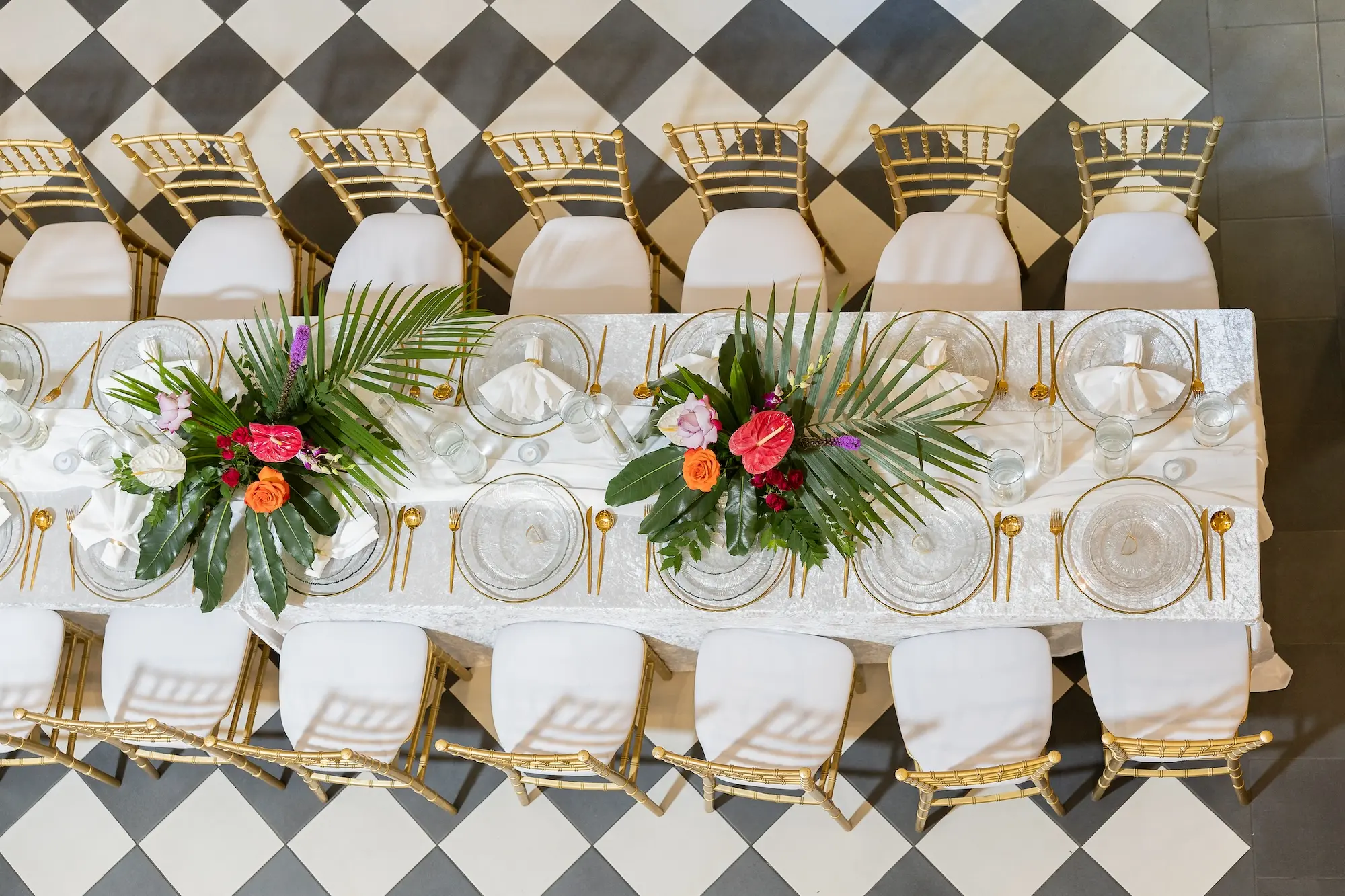 Modern Classic Wedding Ideas | Black and White Checkered Reception Floor Inspiration | White Linens with Gold Chiavari Chairs Ideas | Bright Jewel Toned Coral, Mauves and White Tropical Floral Centerpieces with Deep Green Palms and Greenery Decor Inspiration | Clear Glass Chargers with Gold Rims and Gold Flatware Tablescape Decor Ideas | Tampa Bay Wedding Venue The Spiral Staircase