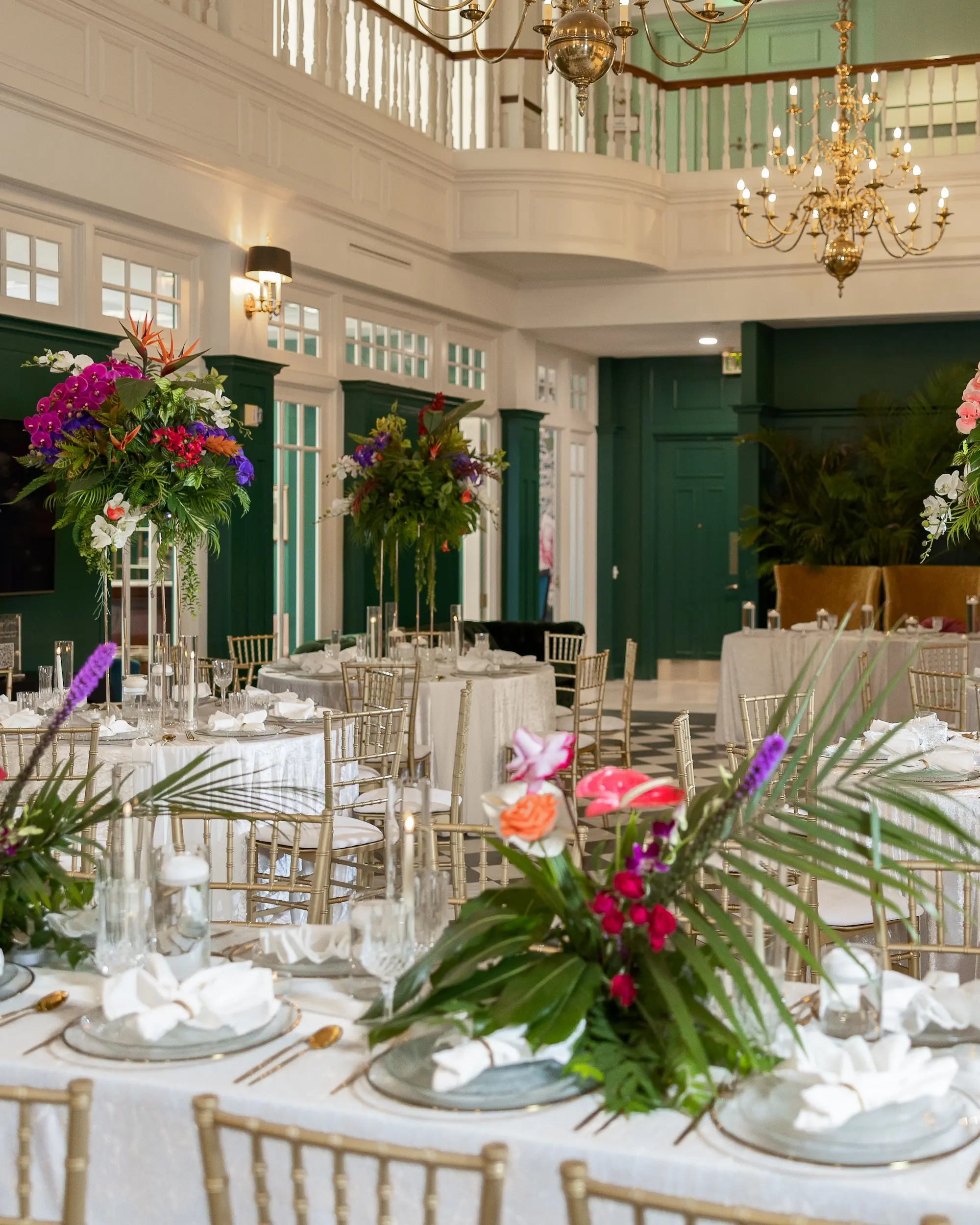 Modern Classic Wedding Ideas | Black and White Checkered Reception Floor Inspiration | White Linens with Gold Chiavari Chairs Ideas | Bright Jewel Toned Coral, Mauves and White Tropical Floral Centerpieces with Deep Green Palms and Greenery Decor Inspiration | Clear Glass Chargers with Gold Rims and Gold Flatware Tablescape Decor Ideas | Tampa Bay Wedding Venue The Spiral Staircase