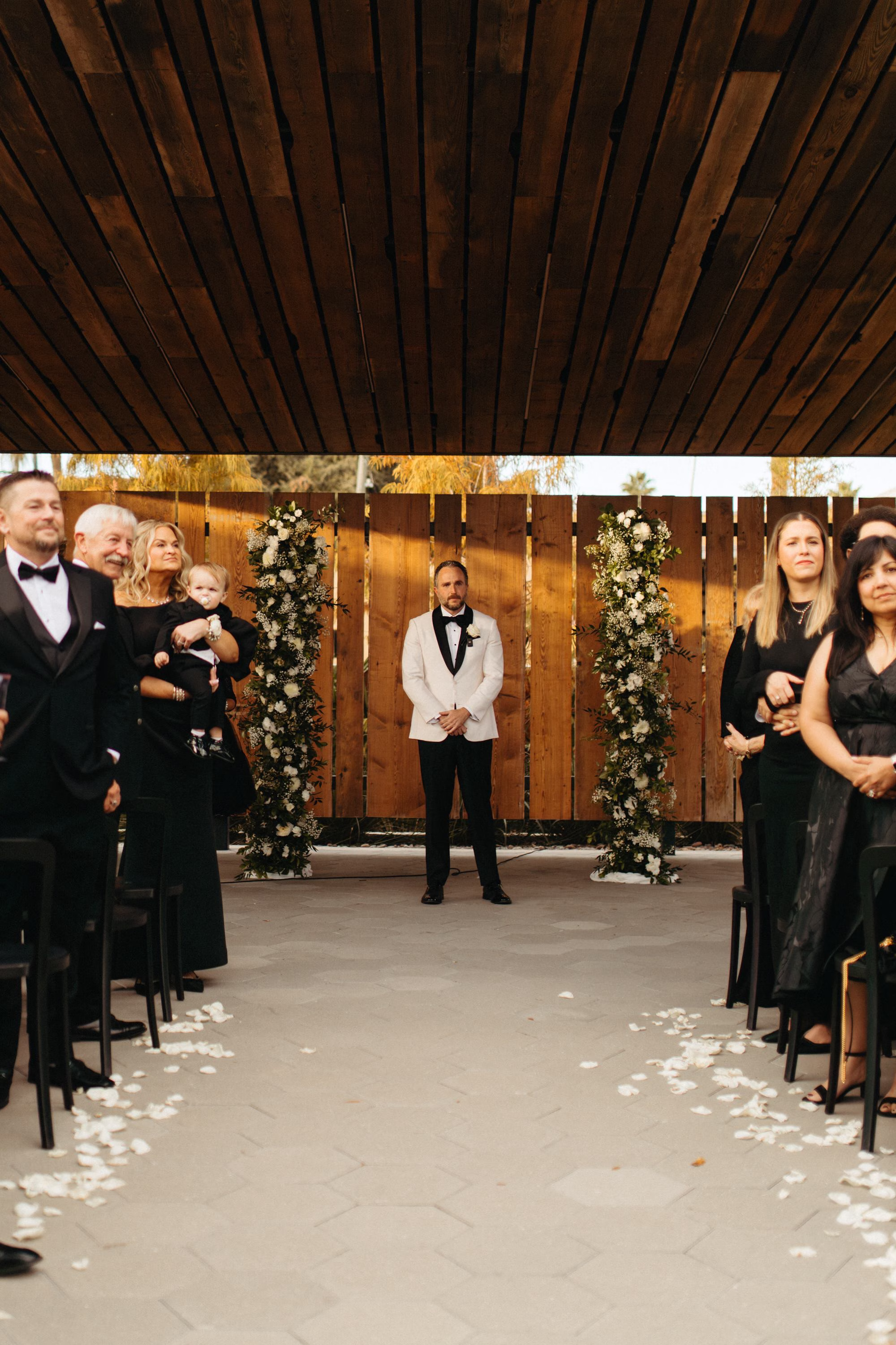 Groom's Reaction to Bride Walking Down Wedding Ceremony Aisle | White Roses and Baby's Breath in Greenery Floral Column Altar Wedding Ceremony Decor Inspiration | White Rose Petals Wedding Ceremony Aisle Decor Ideas | Clearwater Florist Lemon Drops Wedding and Events | Ybor Wedding Venue J.C. Newman Cigar Company