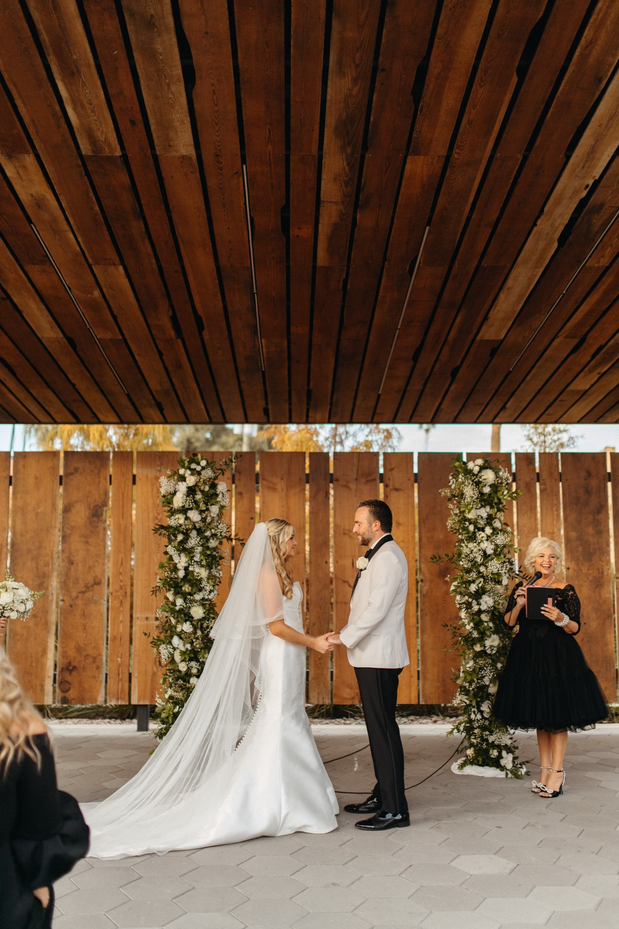Bride and Groom Wedding Ceremony Vow Exchange Wedding Portrait | White Roses and Baby's Breath in Greenery Floral Column Altar Wedding Ceremony Decor Inspiration | Clearwater Florist Lemon Drops Wedding and Events